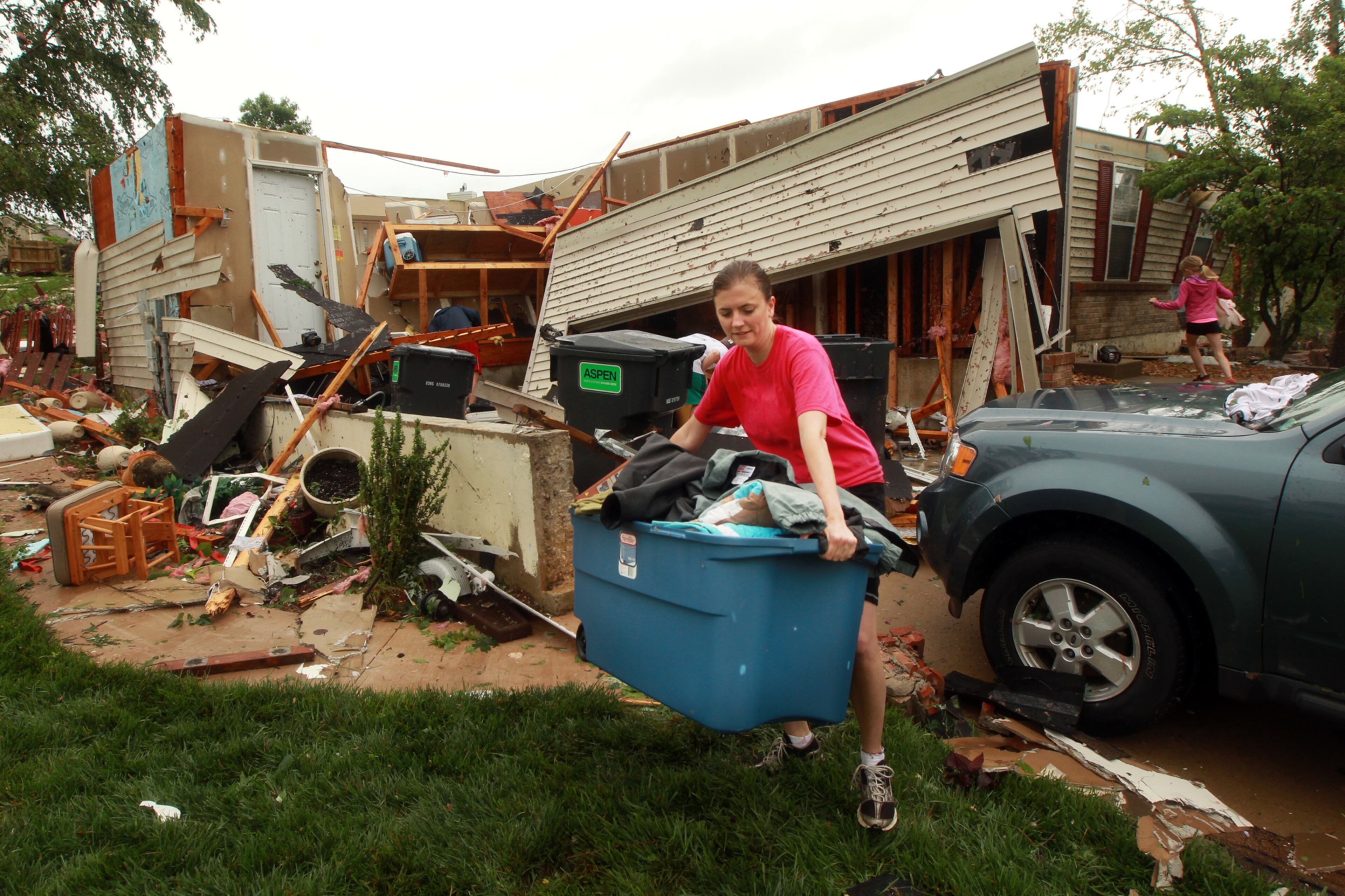 Kristi Clausen helps salvage clothing from her neighbor's destroyed house on Saturday, June 1, 2013 after a overnight storm in St. Charles, Mo. Emergency officials set out Saturday morning to see how much damage a violent burst of thunderstorms and tornadoes caused as it swept across the Midwest overnight. (AP Photo/St. Louis Post-Dispatch, Huy Mach)