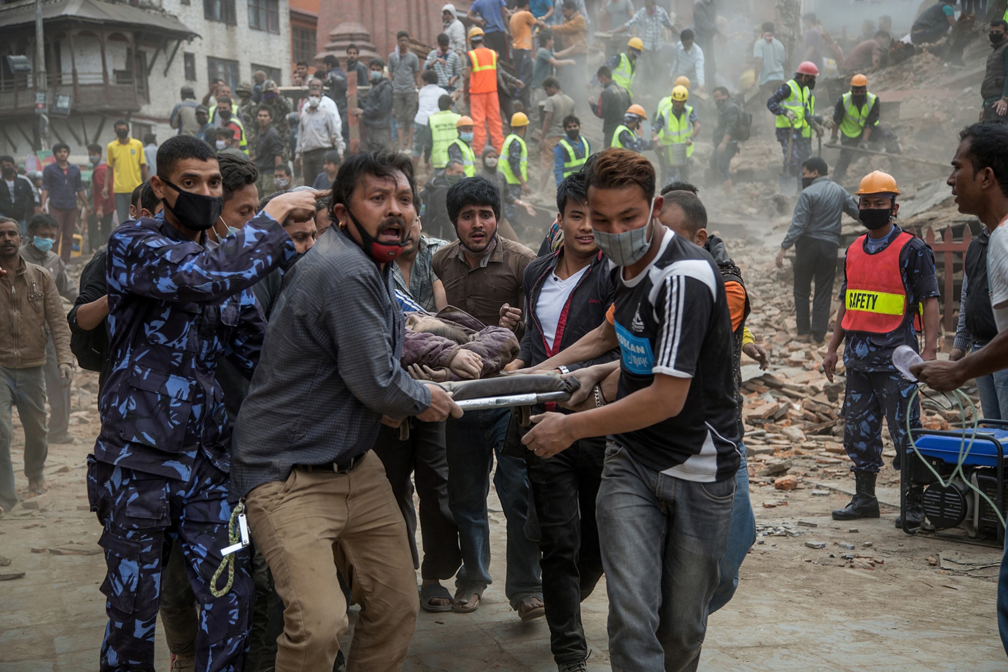 NEPAL EARTHQUAKE--KATHMANDU, NEPAL - APRIL 25: Emergency rescue workers carry a victim on a stretcher after Dharara tower collapsed on April 25, 2015 in Kathmandu, Nepal. More than 100 people have died as tremors hit Nepal after an earthquake measuring 7.9 on the Richter scale caused buildings to collapse and avalanches to be triggered in the Himalayas. Authorities have warned that the death toll is likely to be much higher. (Photo by Omar Havana/Getty Images) *** BESTPIX ***
