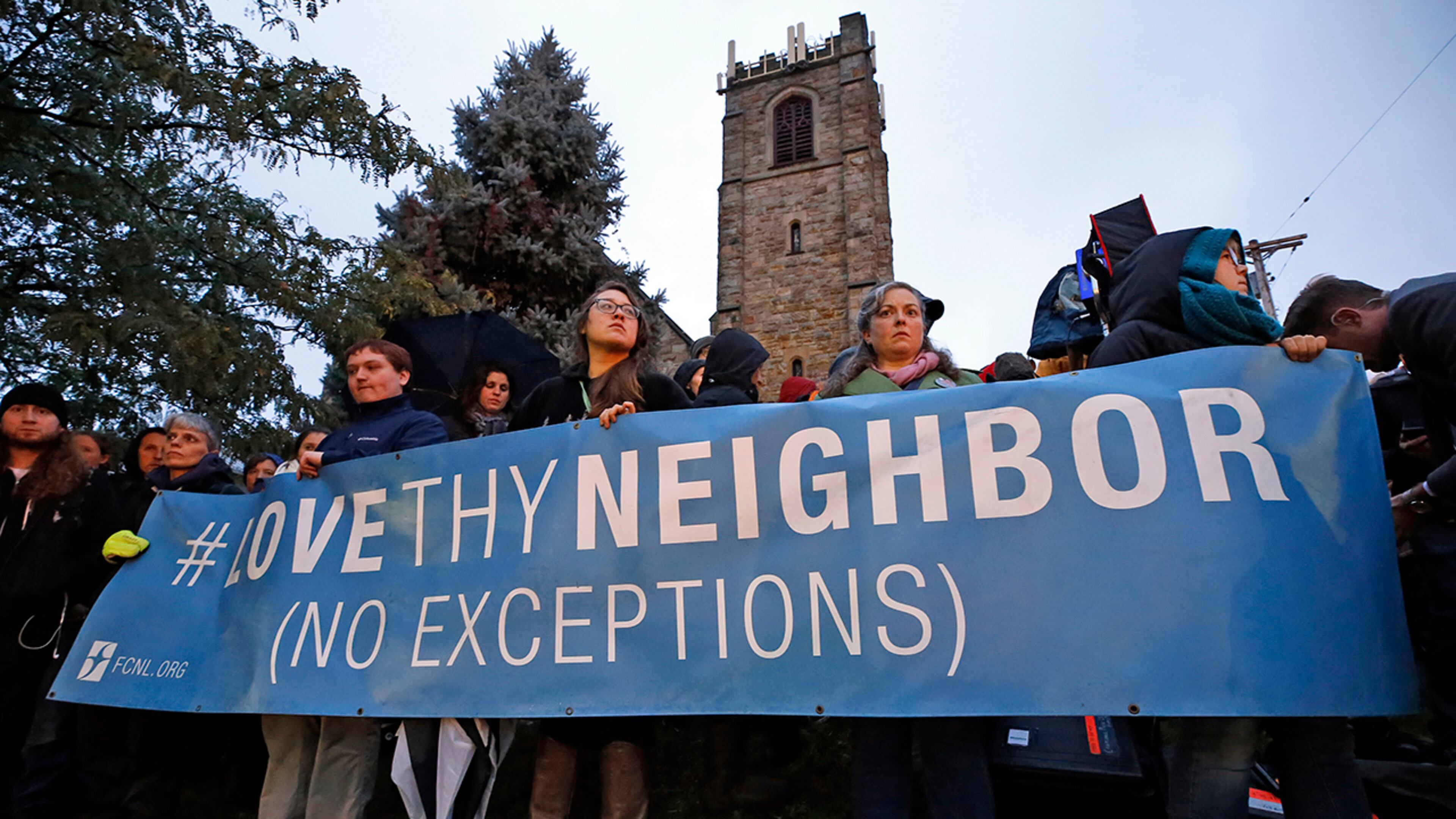 A group holds a sign at the intersection of Murray Ave. and Forbes Ave. in the Squirrel Hill section of Pittsburgh, during a memorial vigil for the victims of the shooting at the Tree of Life Synagogue where a shooter opened fire, killing multiple people and wounding others, including several police officers, Saturday, Oct. 27, 2018. (AP Photo/Gene J. Puskar)