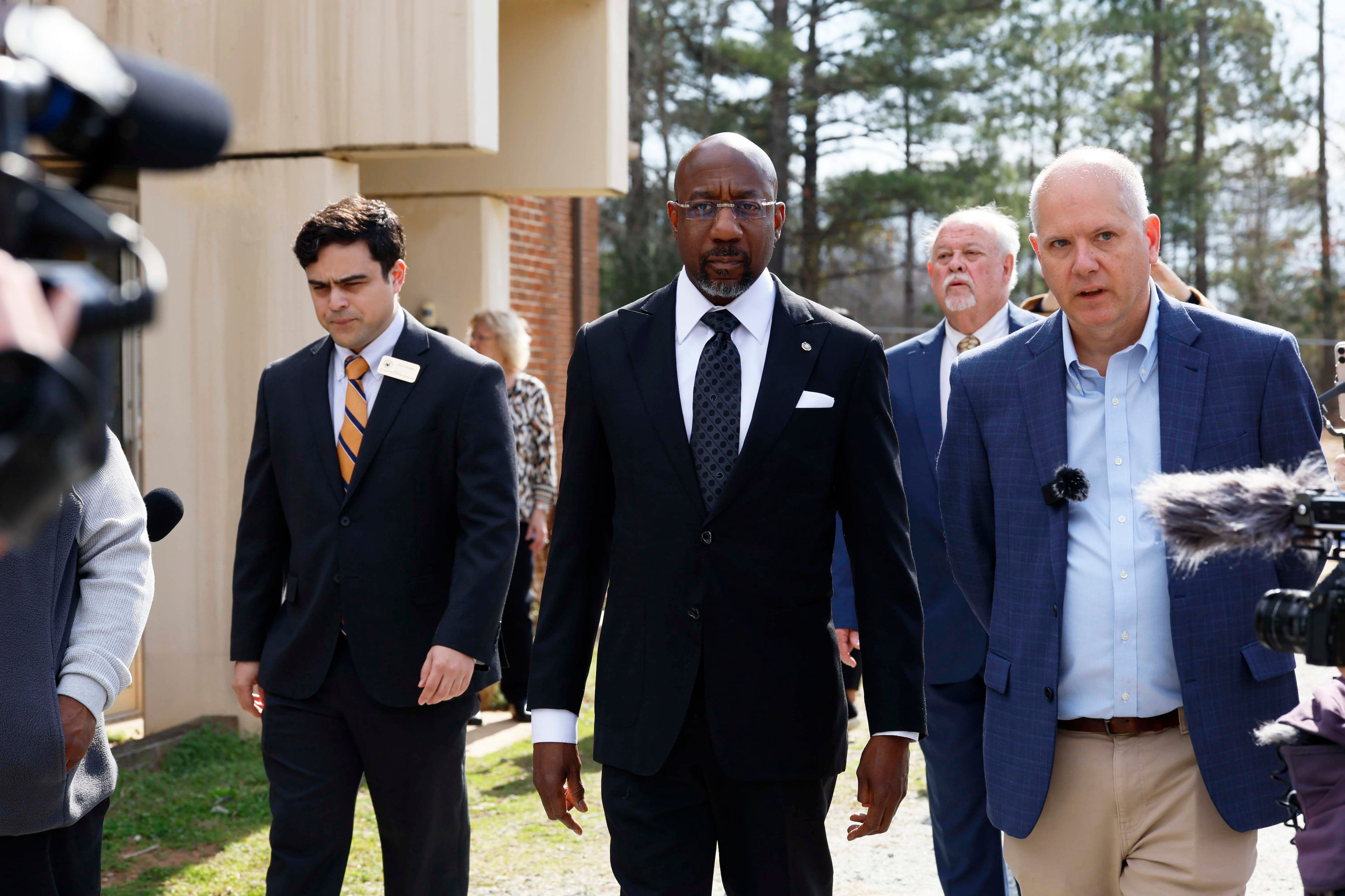 Social Circle City Manager Eric Taylor (right) walks with U.S. Sen. Raphael Warnock (center), D-Ga., as they tour a city water treatment facility on Monday, March 2, 2026. Social Circle officials say the administration's plan to use a warehouse as an immigration detention facility would put too much pressure on the city's water and sewer resources and remove more than $1 million from its tax rolls. (Miguel Martinez/AJC)