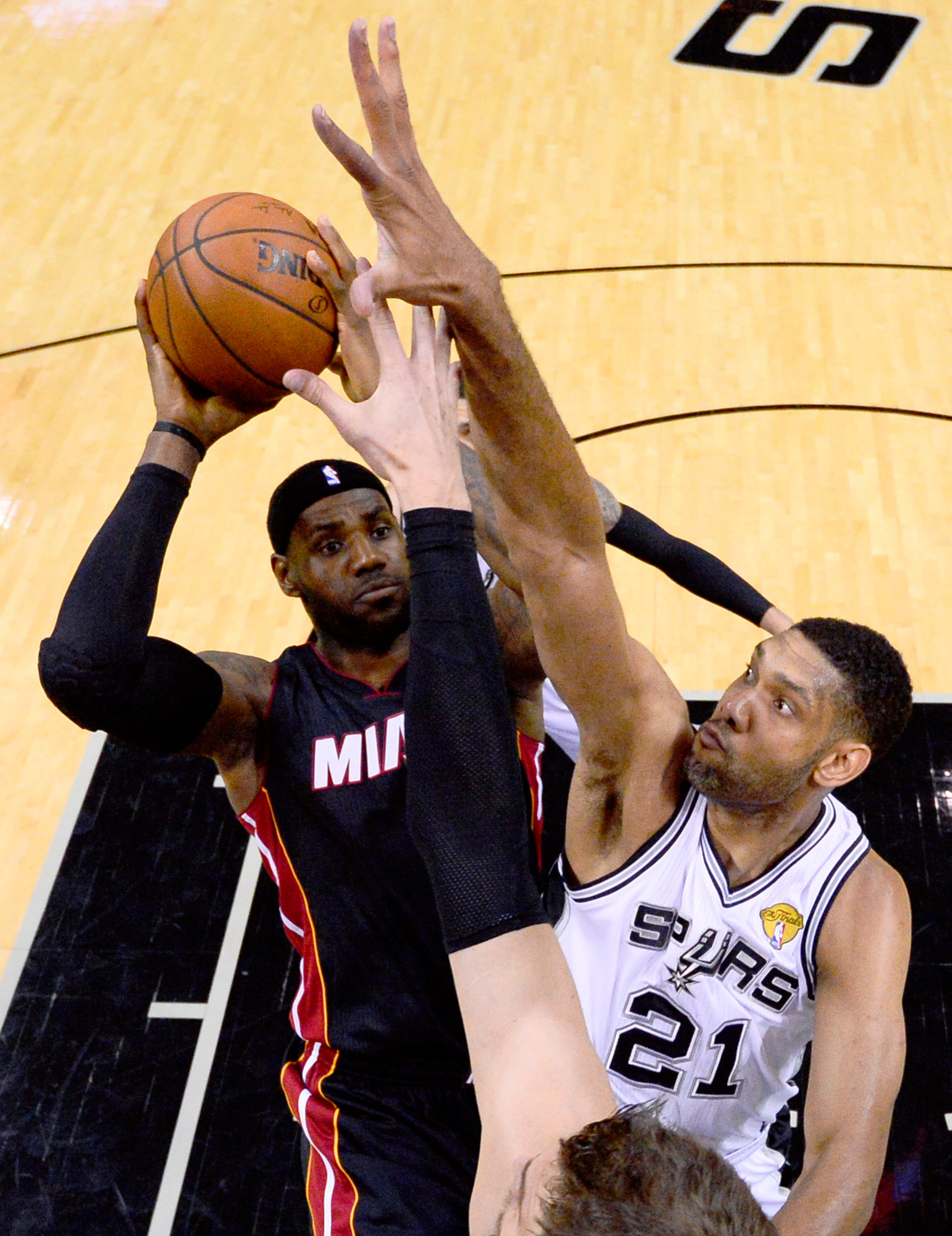 Miami Heat forward LeBron James shoots over San Antonio Spurs forward Tim Duncan (21) and Tiago Splitter, bottom during the first half in Game 2 of the NBA basketball finals on Saturday, Nov. 8, 2014, in San Antonio. (AP Photo/Larry W. Smith, pool)