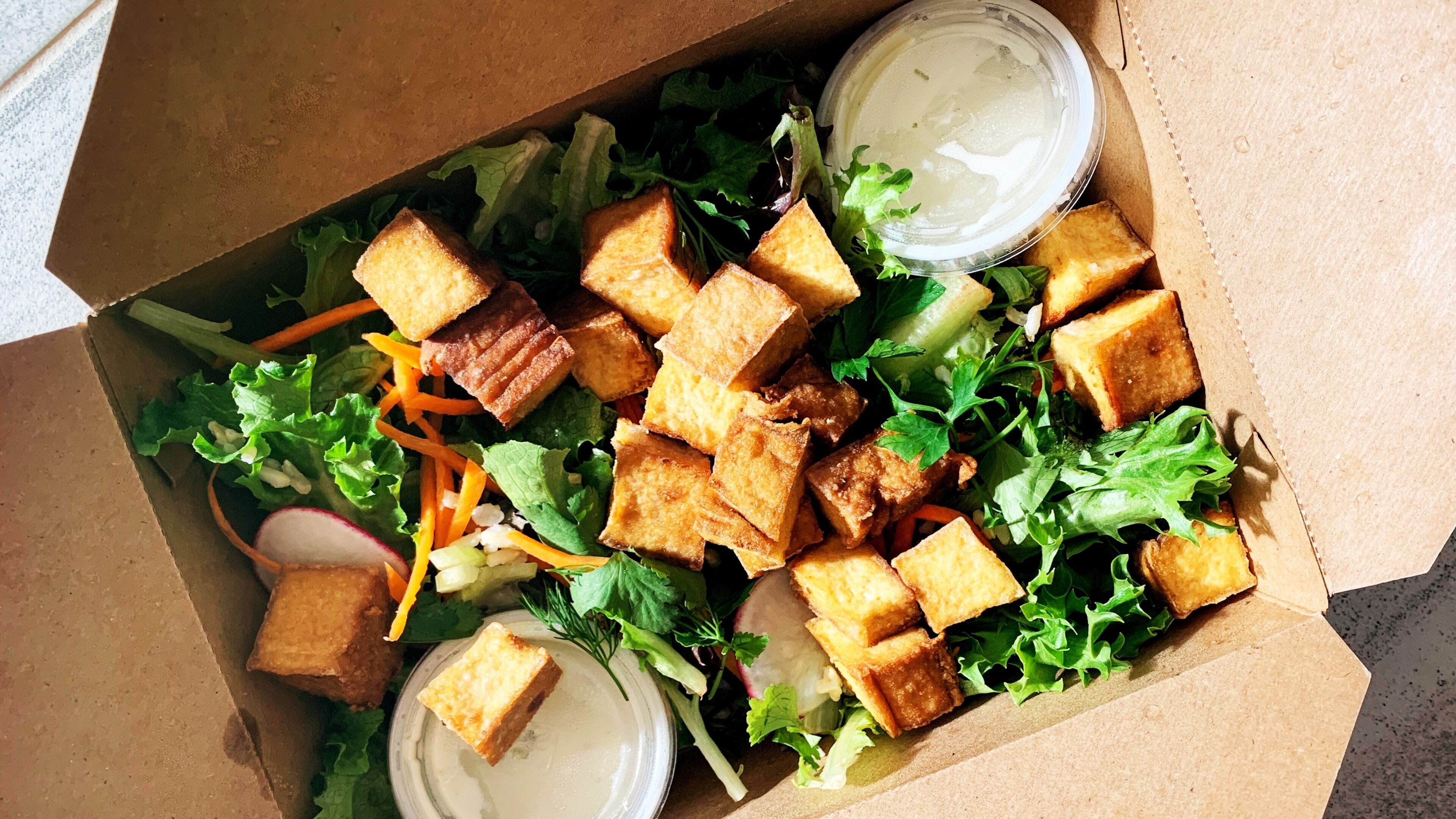 The tropical salad with smoked tofu from El Super Pan is made with local greens and topped with avocado, cherry tomatoes, palm hearts, green olives and pepitas. Henri Hollis for The Atlanta Journal-Constitution