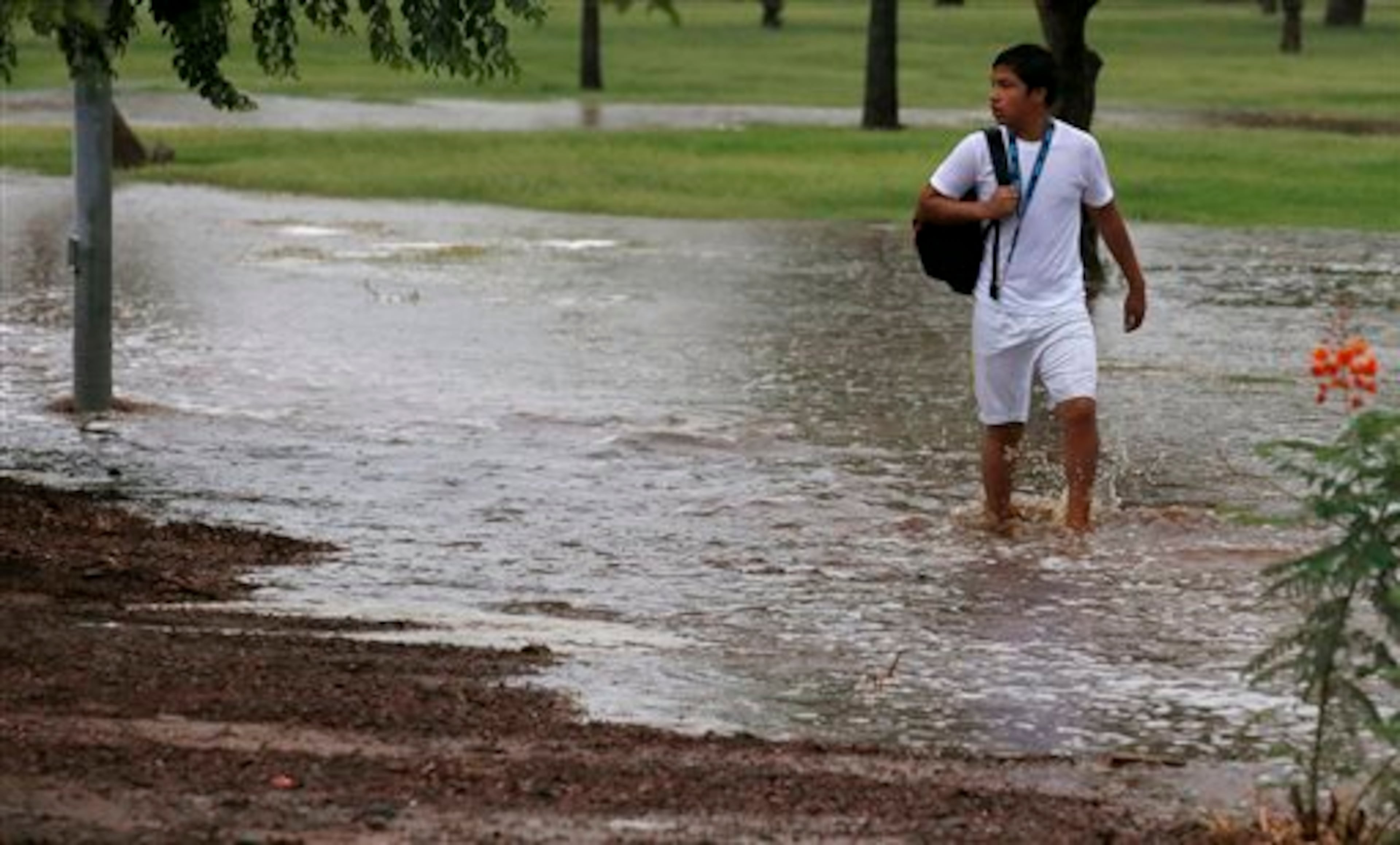 A student tries to walk along a flooded sidewalk to a non-flooded street so he can be picked up by his parents after schools were closed as heavy rains pour down causing severe flooding Monday, Sept. 8, 2014, in Phoenix. Storms that flooded several Phoenix-area freeways and numerous local streets during the Monday morning commute set an all-time record for rainfall in Phoenix in a single day. (AP Photo/Ross D. Franklin)