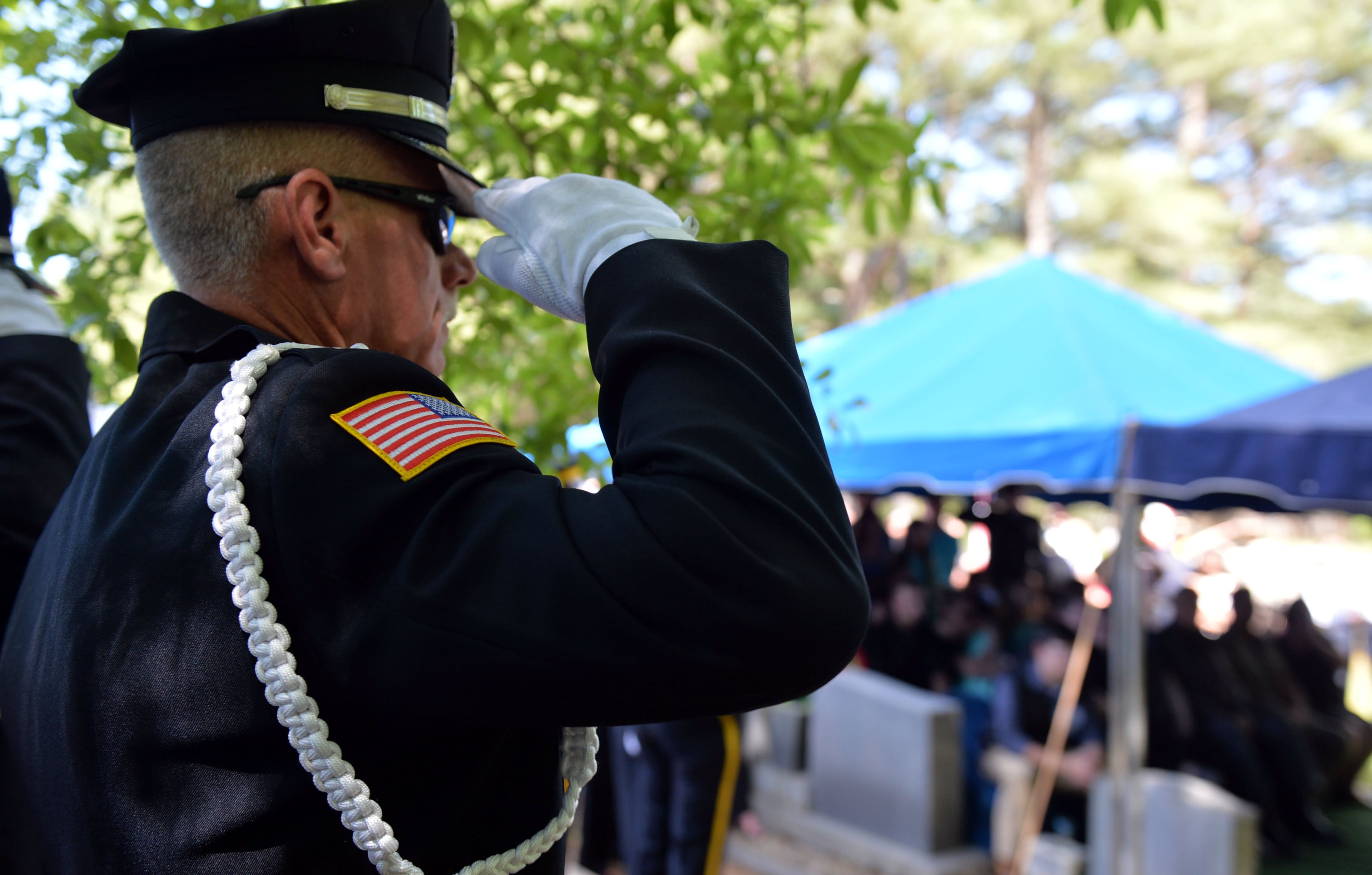 An Eatonton Police officer salutes as "Taps" is played at the A.E. Carter Funeral Home in Madison, Ga.