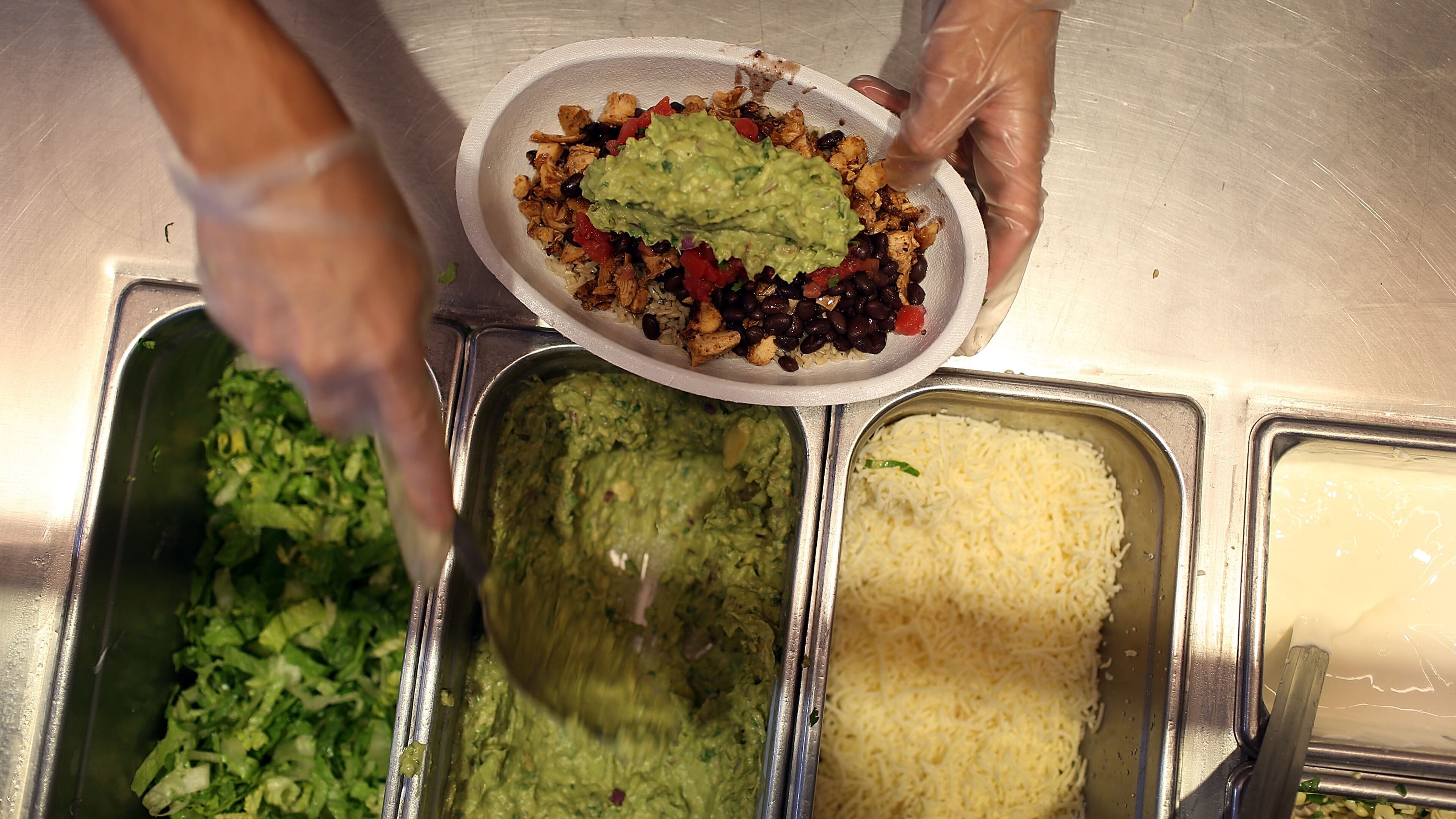 MIAMI, FL - APRIL 27: Chipotle restaurant workers fill orders for customers on the day that the company announced it will only use non-GMO ingredients in its food on April 27, 2015 in Miami, Florida. (Photo by Joe Raedle/Getty Images)