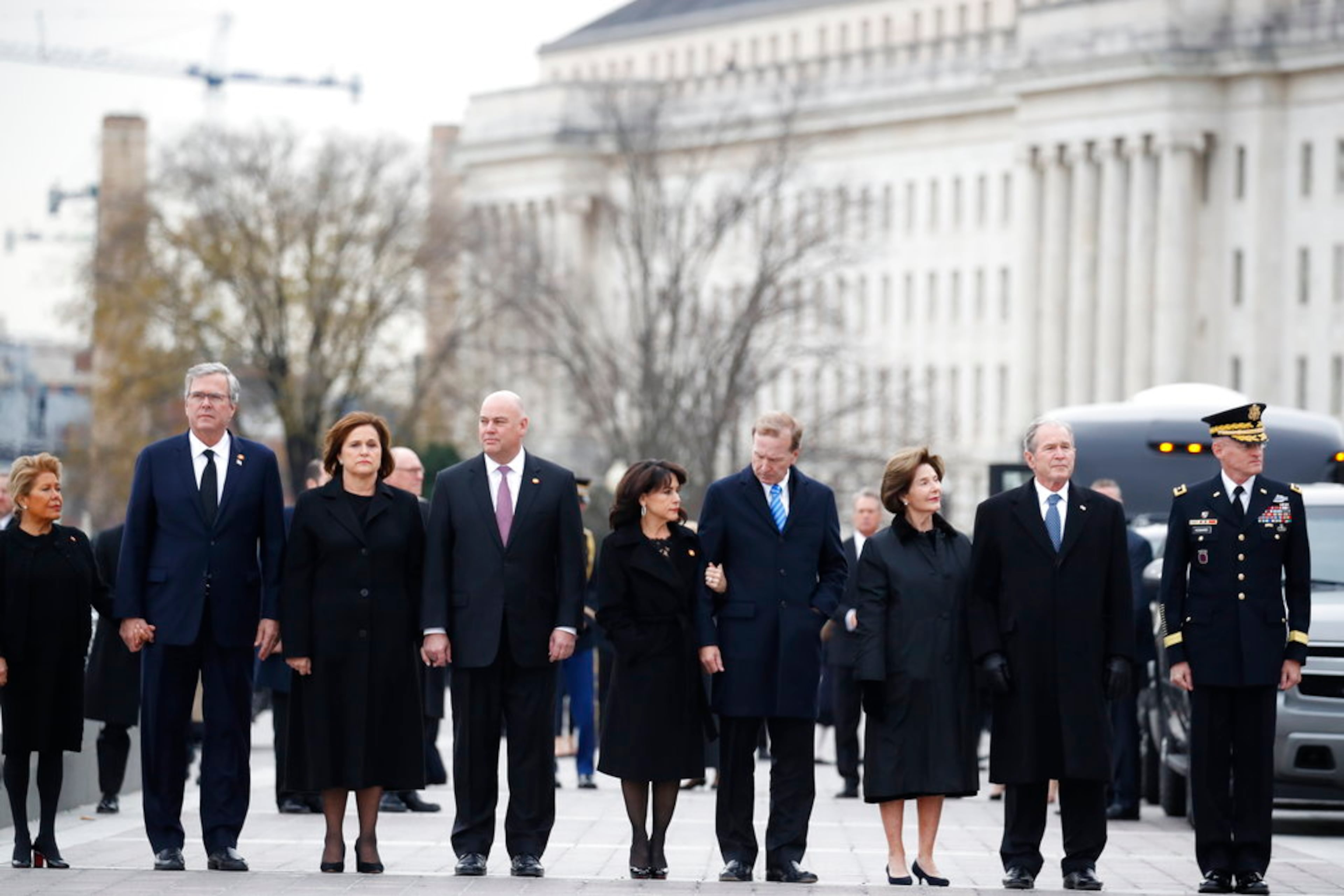 From right, former President George W. Bush, second from right, former first lady Laura Bush, Neil Bush, Sharon Bush, Bobby Koch, Doro Koch, Jeb Bush and Columba Bush, stand just prior to the flag-draped casket of former President George H.W. Bush being carried by a joint services military honor guard from the U.S. Capitol, Wednesday, Dec. 5, 2018, in Washington. (AP Photo/Alex Brandon, Pool)