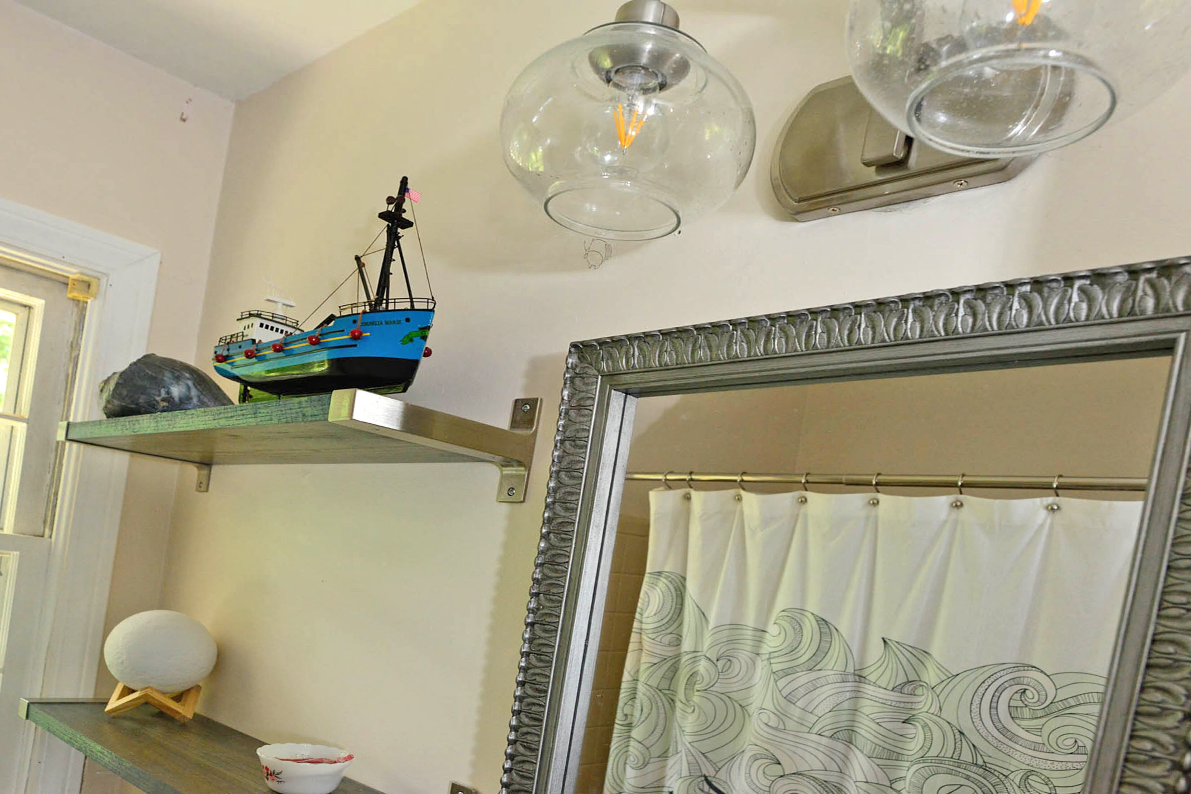 Whimsy flows into the master bathroom with a model boat and an illustrated sea design from ModCloth. The ship on the shelf is a miniature replica of the Cornelia Marie from the TV series, "Deadliest Catch."