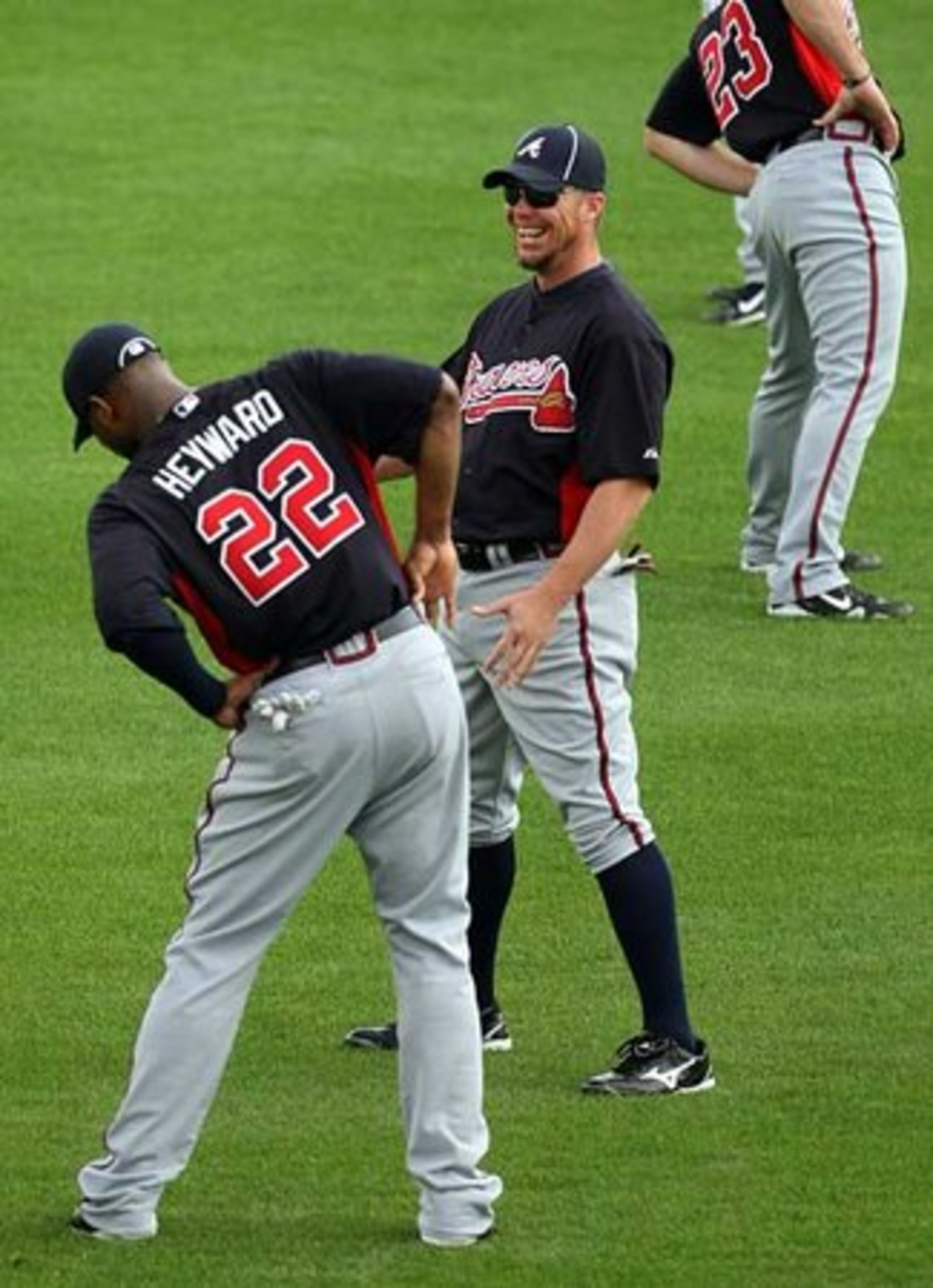 Jason Heyward (22) stretches as third baseman Chipper Jones laughs at a joke.