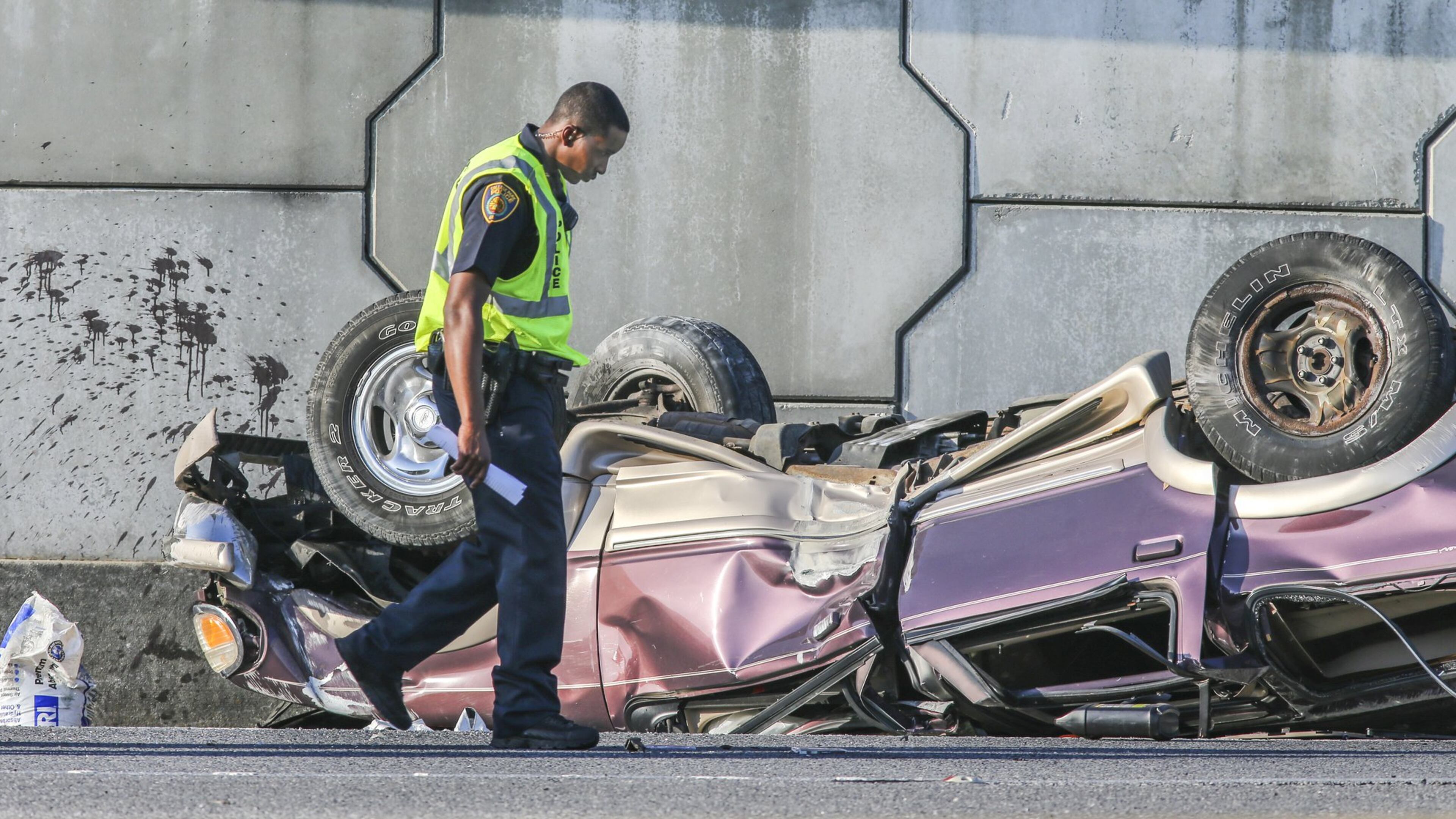 College Park police investigate the scene of an accident the morning of April 9. The northbound lanes of I-85 and the exit ramp at Riverdale Road backed up following a fatal wreck involving a sport utility vehicle that police said fell 15 feet off adjacent I-285. (JOHN SPINK / JSPINK@AJC.COM)