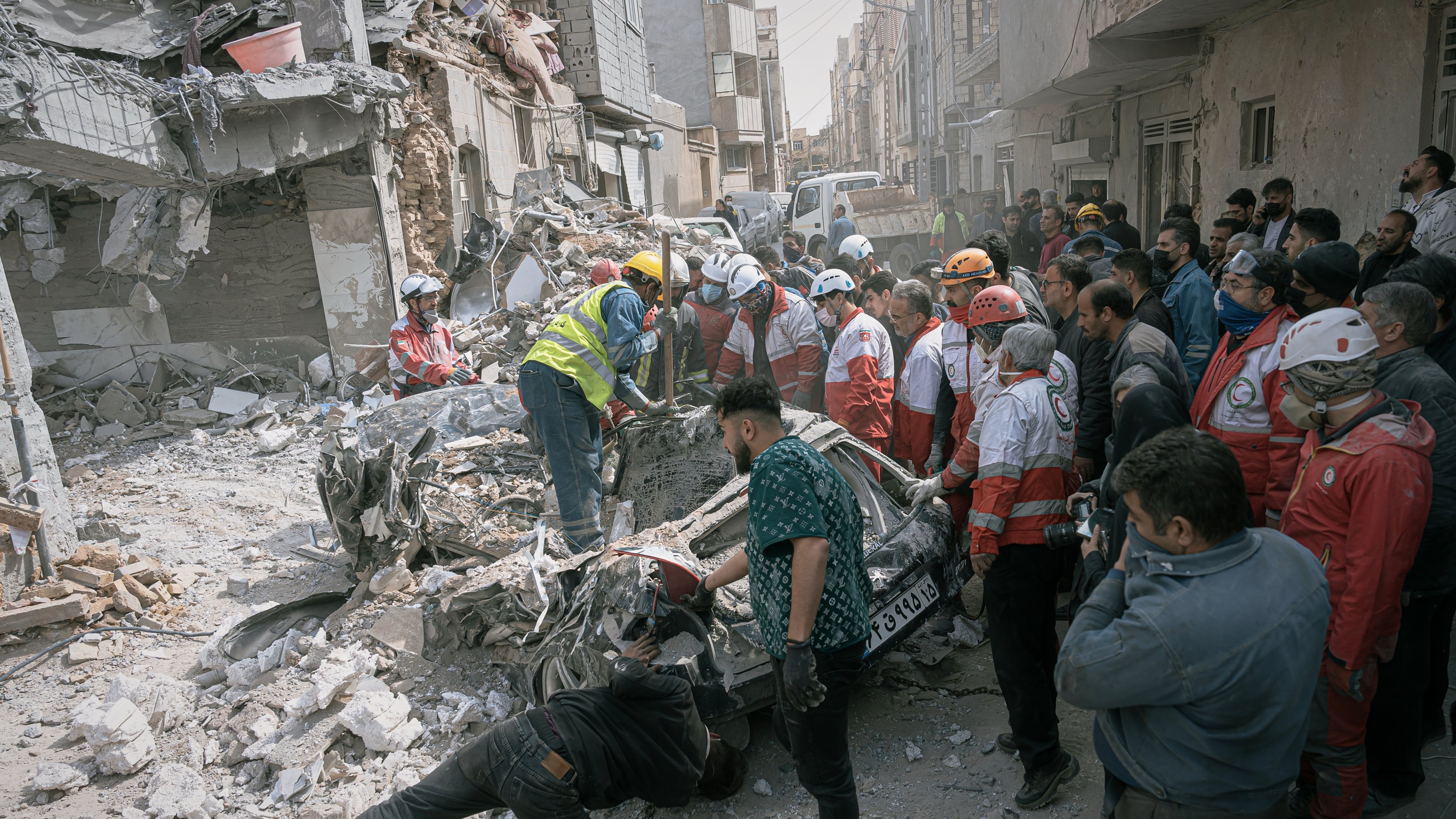 First responders inspect a destroyed car at the site of a residential building hit in an overnight strike during the U.S.-Israeli military campaign in Tabriz, East Azerbaijan Province, northwestern Iran, Tuesday, March 24, 2026. (AP Photo/Matin Hashemi)
