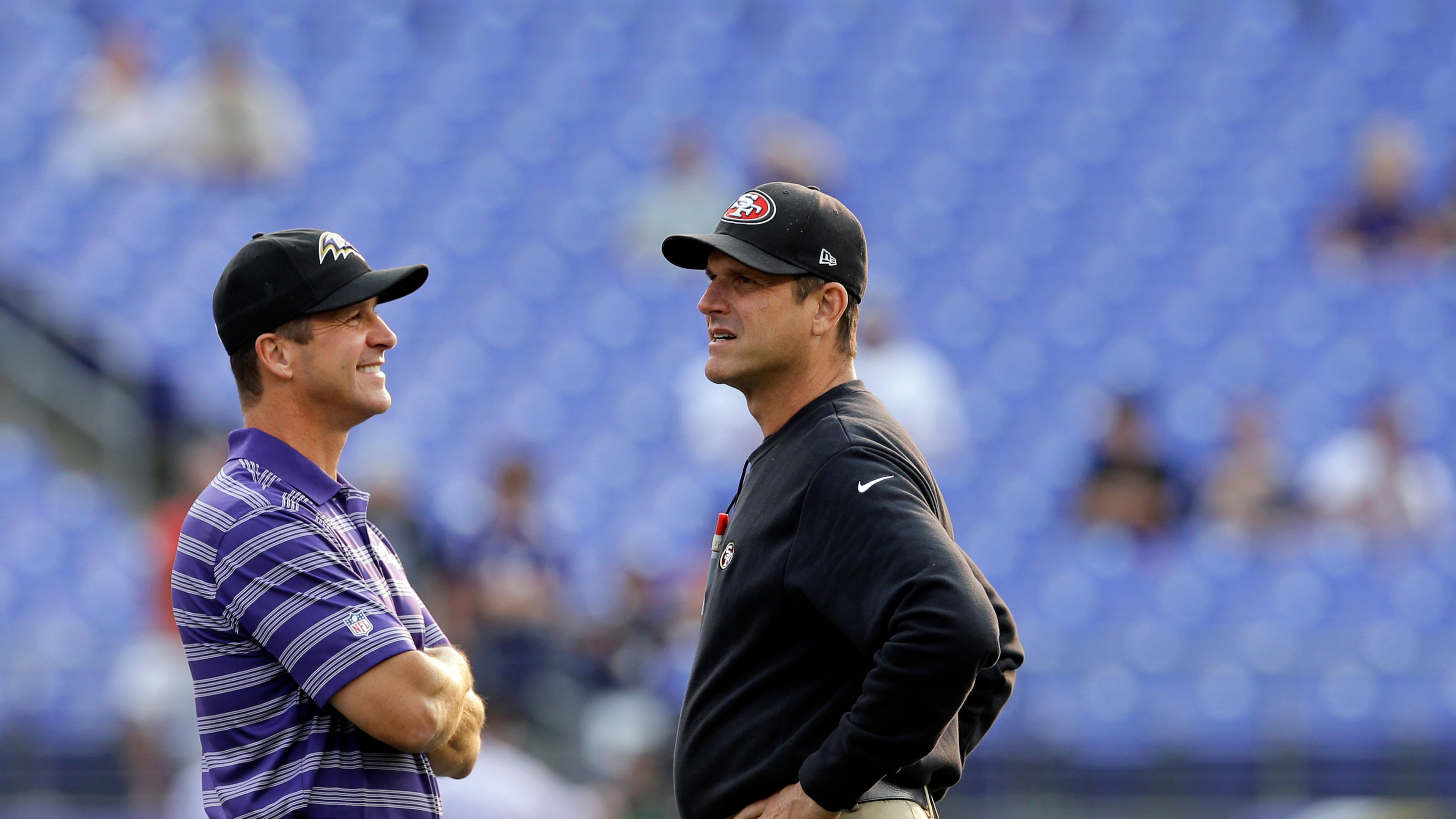 FILE - Baltimore Ravens head coach John Harbaugh, left, and San Francisco 49ers head coach Jim Harbaugh chat before an NFL preseason football game, Aug. 7, 2014, in Baltimore. (AP Photo/Patrick Semansky, File)