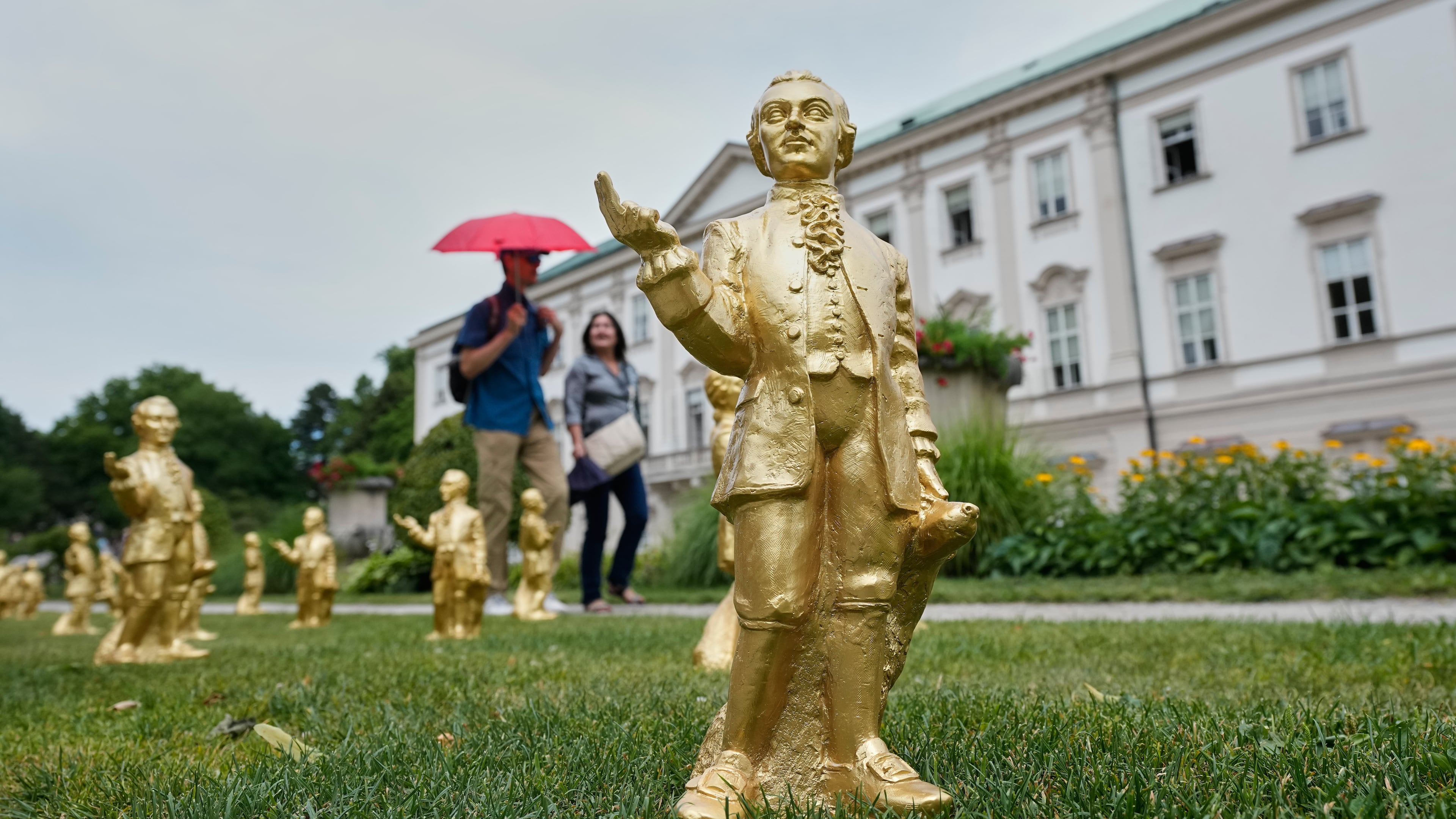 FILE - People walk by some of the 400 gold colored plastic Mozart sculptures by German artist Ottmar Hoerl from Nuremberg for the 270th birthday of composer Wolfgang Amadeus Mozart in Salzburg, Austria, Wednesday, July 15, 2026. (AP Photo/Matthias Schrader, File)