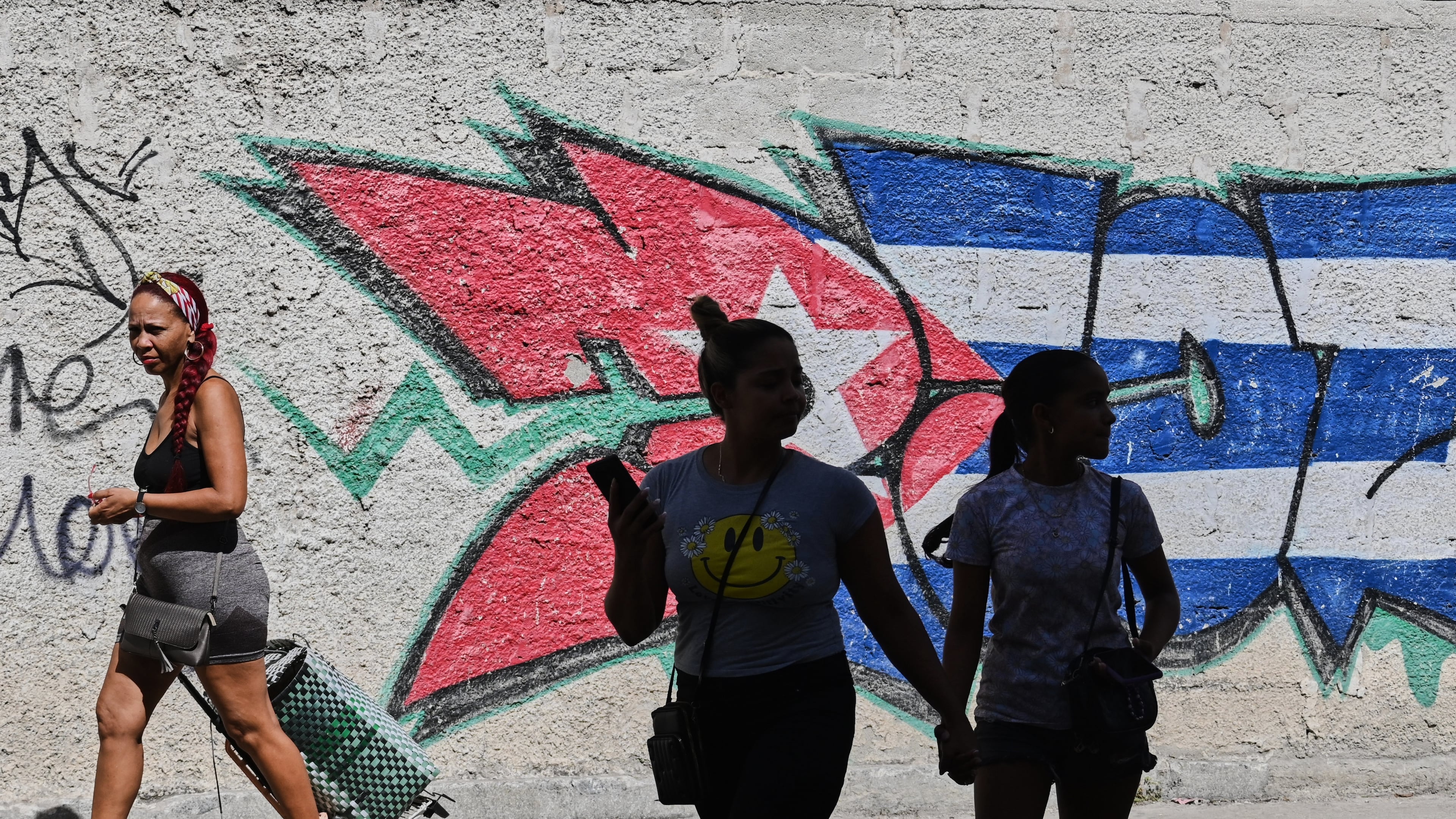 People walk past graffiti in the colors of the Cuban flag in Havana, Cuba, Wednesday, June 17, 2026. (AP Photo/Jorge Luis Banos)