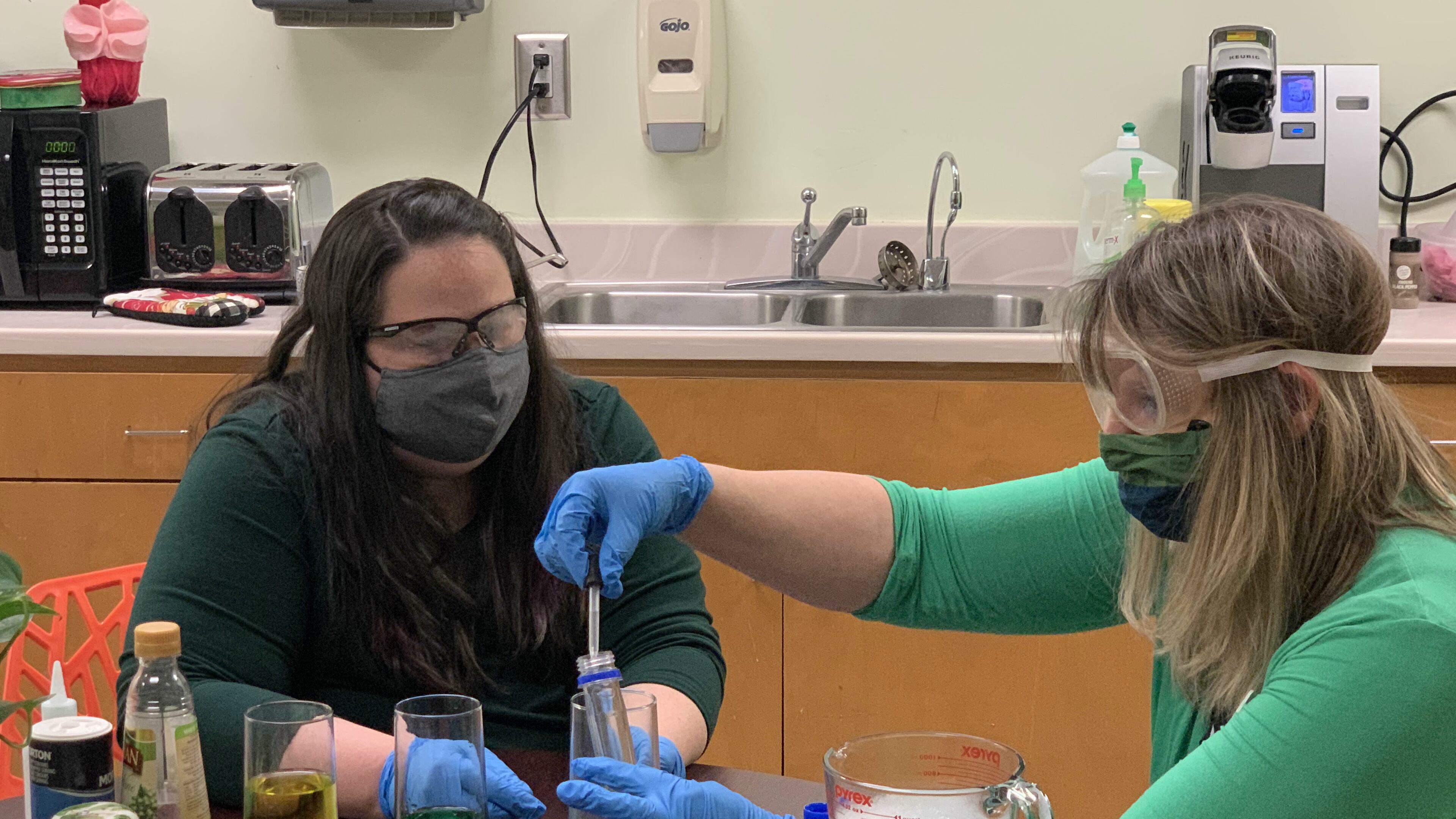 Kitchen Chemistry is a weekly virtual chemistry class sponsored by the Gwinnett County Public Library taught by Katharine Russell (left) and Sarah Martin (right). Working together on the “Rainbow Density Column” experiment Martin is using a dropper to extract the blue sugar water to the rainbow column. This experiment took a few tries.