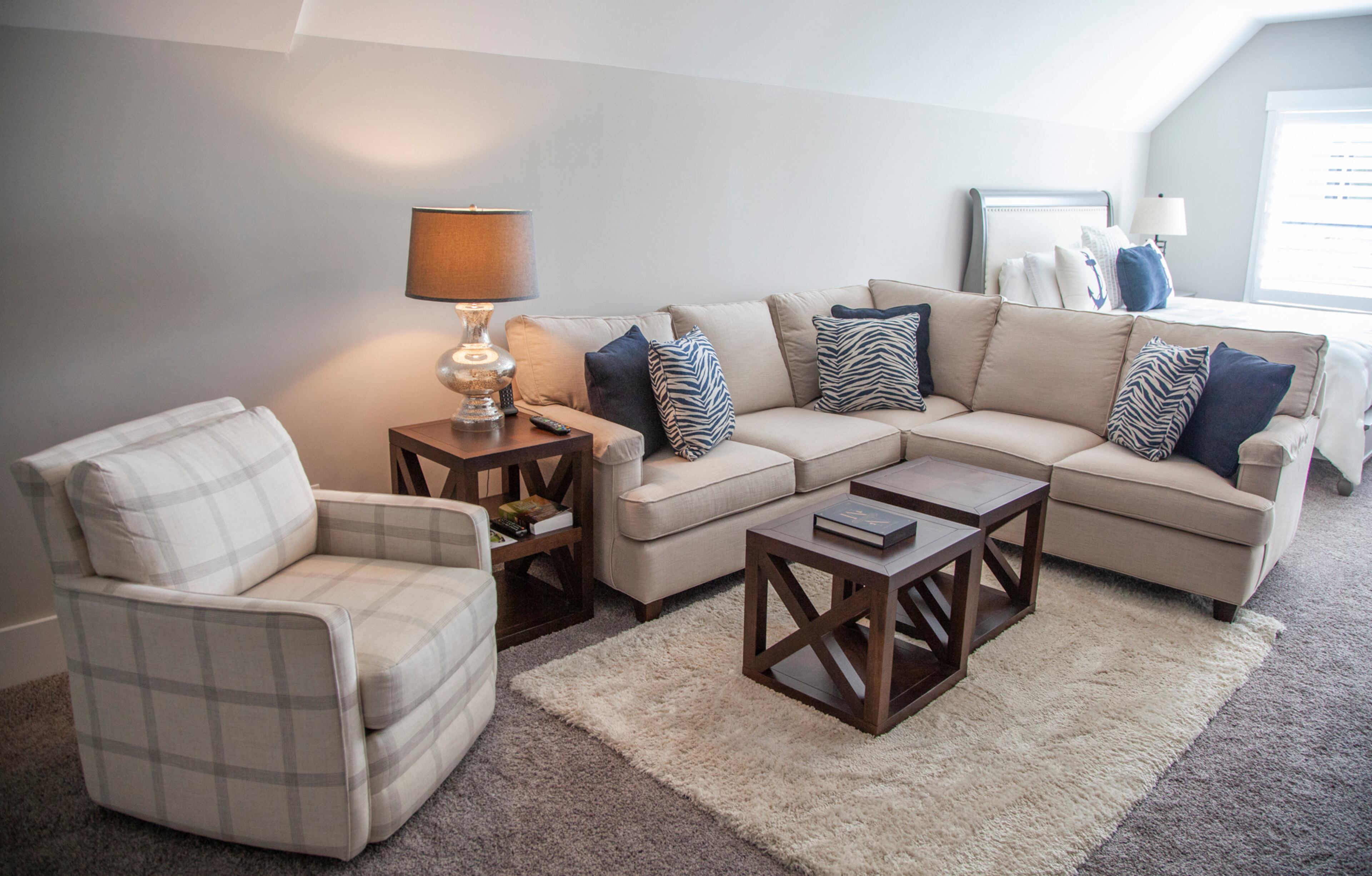 Upstairs is a guest bedroom with its own sitting area. The couch and the pair of coffee tables are from Bassett, as well as the accent pillows. Text by Kat Khoury/Fast Copy News Service. Photo by Reann Huber.