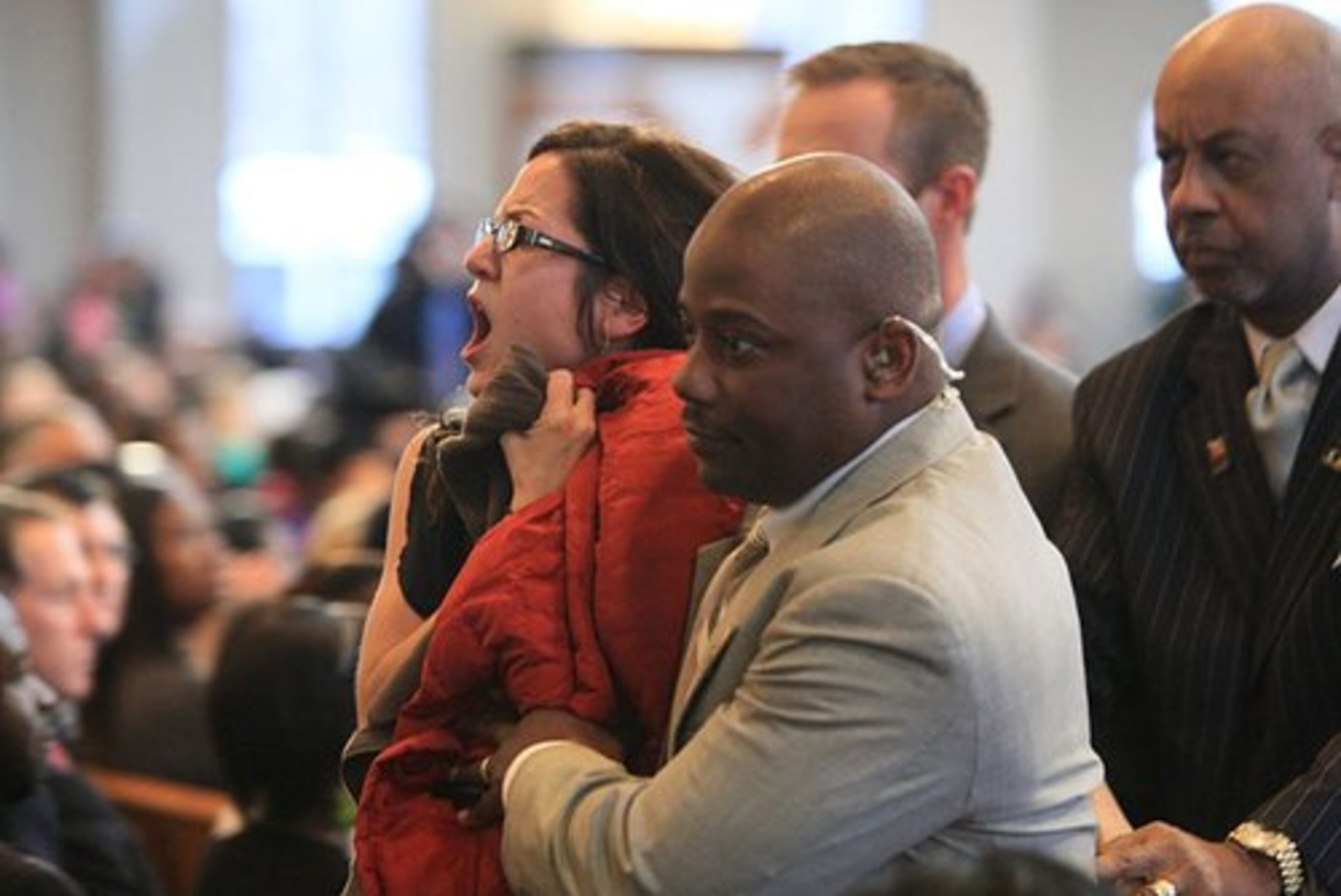 A protester is escorted out of the service after she stood up to holler as Warren began speaking.