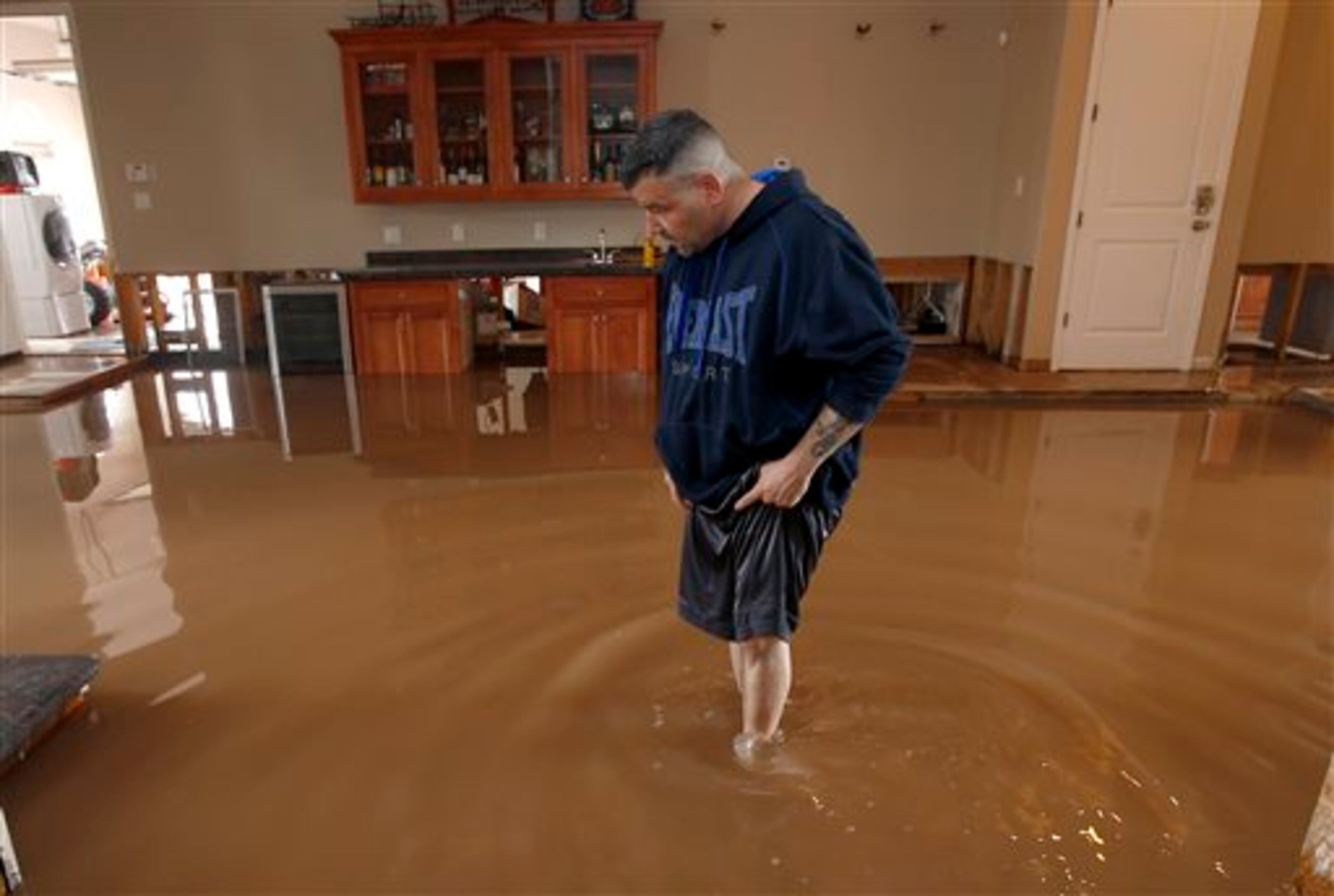 A dismayed Nick Kriaris wades through his flooded home after heavy rains caused severe flash flooding Monday, Sept. 8, 2014, in Phoenix. His home has flooded three times in the past month, and he had just fixing the damage in his home from the previous two monsoon storm floodings when the storm hit. The Monday morning storm set an all-time record for rainfall in Phoenix in a single day. (AP Photo/Ross D. Franklin)
