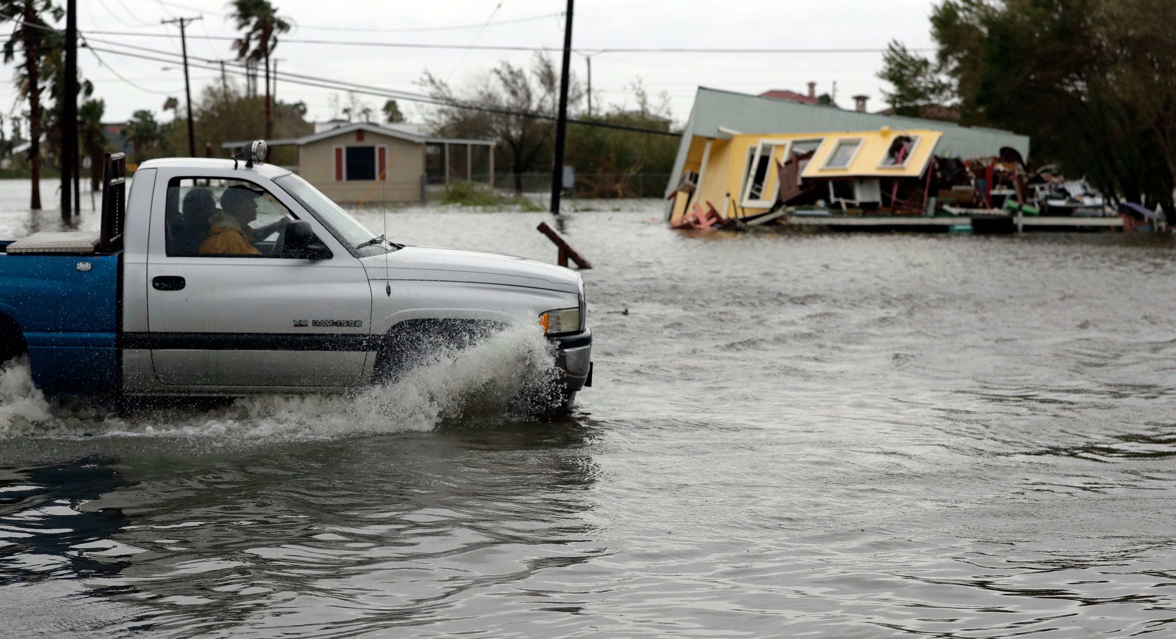 A truck in flood waters passes a home damaged in the wake of Hurricane Harvey, Saturday, Aug. 26, 2017, in Aransas Pass, Texas. Harvey rolled over the Texas Gulf Coast on Saturday, smashing homes and businesses and lashing the shore with wind and rain so intense that drivers were forced off the road because they could not see in front of them. (AP Photo/Eric Gay)
