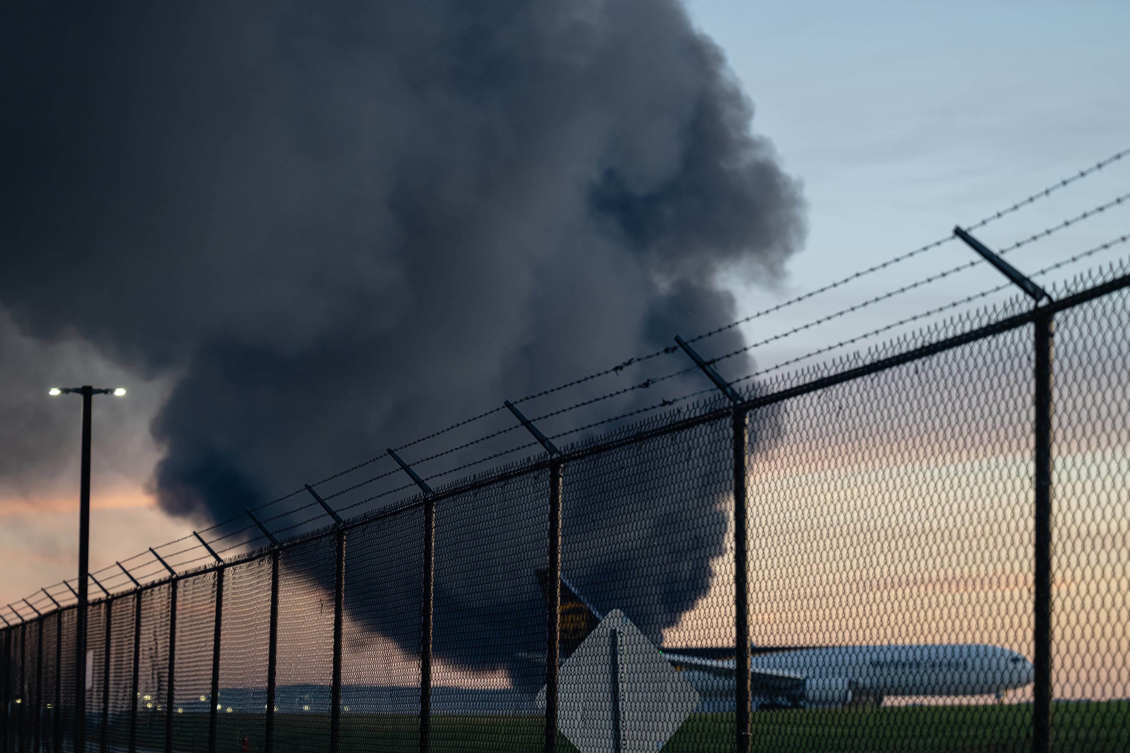 A UPS Boeing 737 is seen parked while a plume of smoke from the nearby UPS cargo plane crash is seen at Louisville Muhammad Ali International Airport on Tuesday, Nov. 4, 2025, in Louisville, Ky. (Jon Cherry/AP)