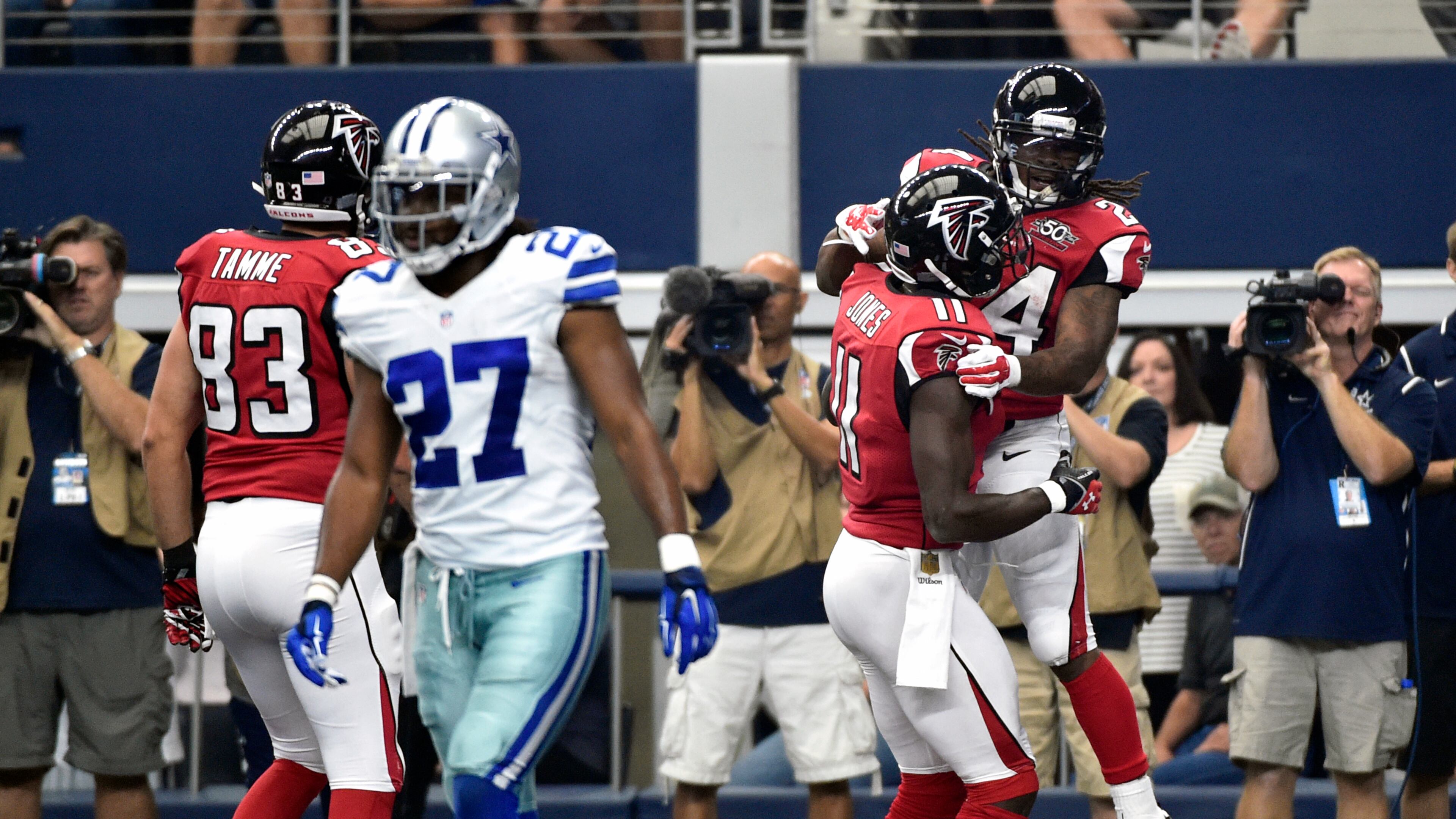 Dallas Cowboys free safety J.J. Wilcox (27) walks away as Atlanta Falcons' Jacob Tamme (83) and Julio Jones (11) celebrate with Devonta Freeman (24) after Freeman scored a touchdown in the first half of an NFL football game on Sunday, Sept. 27, 2015, in Arlington, Texas. (AP Photo/Michael Ainsworth)