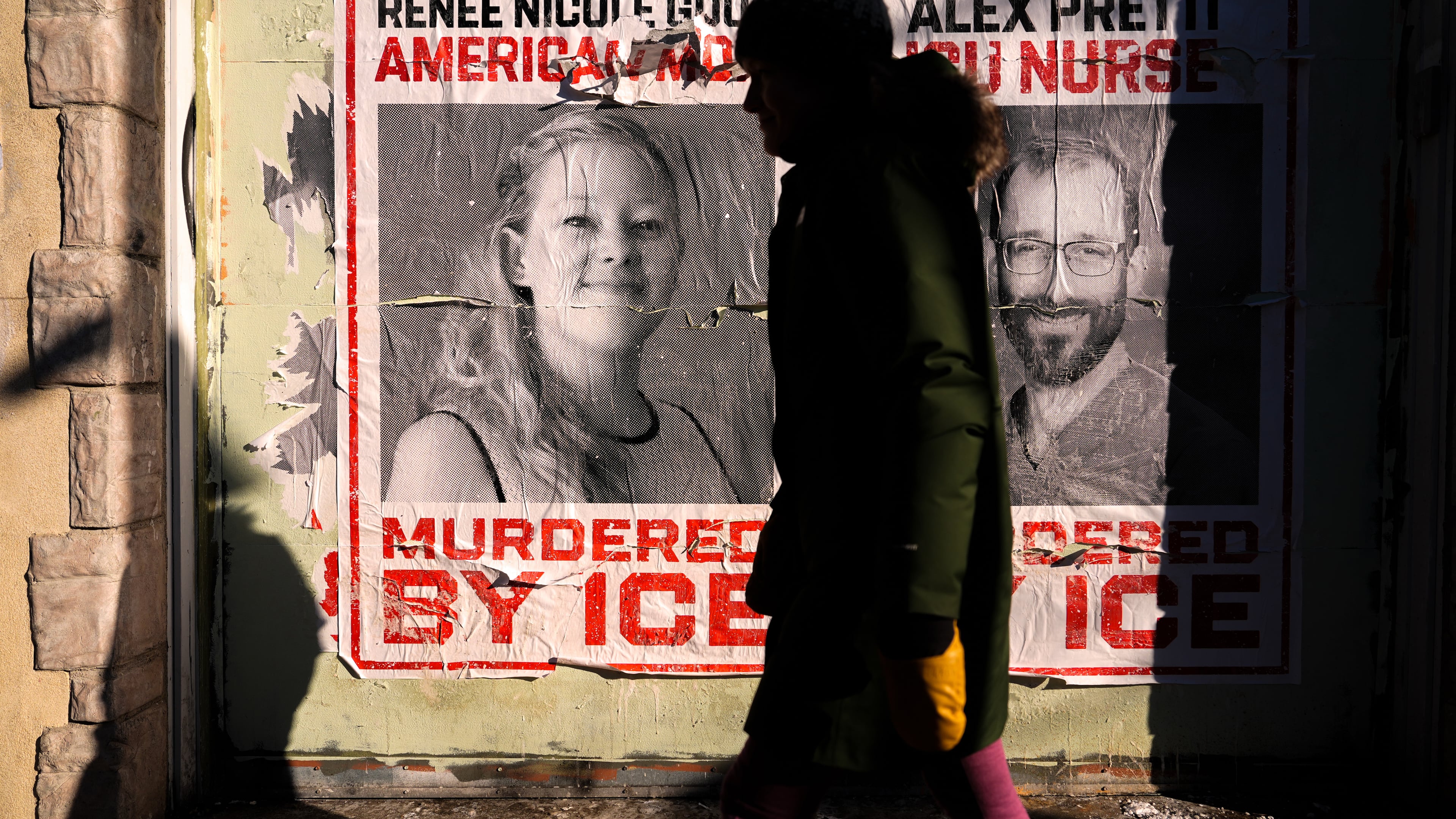 FILE - A woman walks by posters of Renee Good and Alex Pretti during a solidarity bike ride for Pretti, Jan. 31, 2026, in Minneapolis. (AP Photo/Julia Demaree Nikhinson, File)