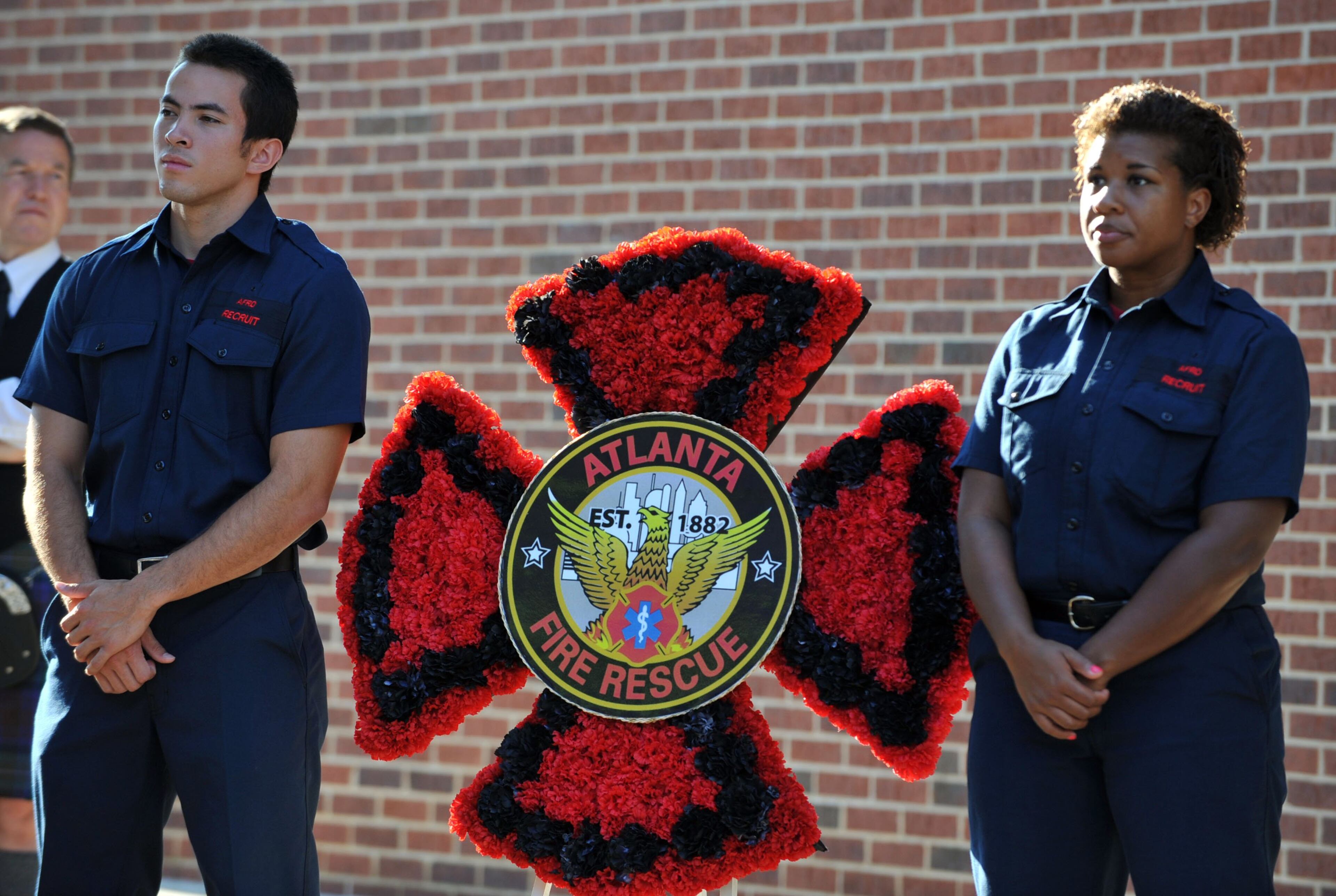 Atlanta Fire Rescue recruits Hoang Dang (left) and Pamela Amerson stand at attention with the departmental wreath before the ceremony. Officials with the Atlanta Police Department and Atlanta Fire Rescue Department honored the 12th anniversary of the Sept. 11, 2001, tragedy during a ceremony at Public Safety Headquarters on Sept. 11, 2013.