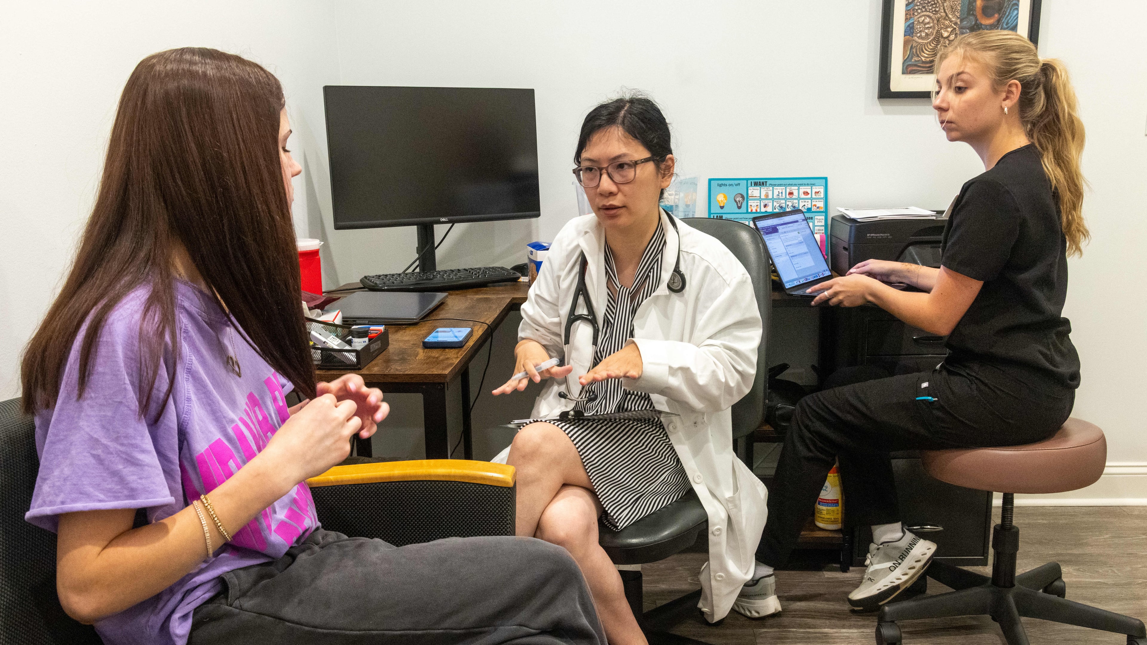 Patient Isabella Burke (from left) listens to Dr. Zheyu Lu as medical scribe Sarah Taylor takes notes during a visit to the Forsyth Community Clinic in Cumming. The clinic is the only wholly free health care clinic for uninsured adults in Forsyth County. (Phil Skinner for the AJC)