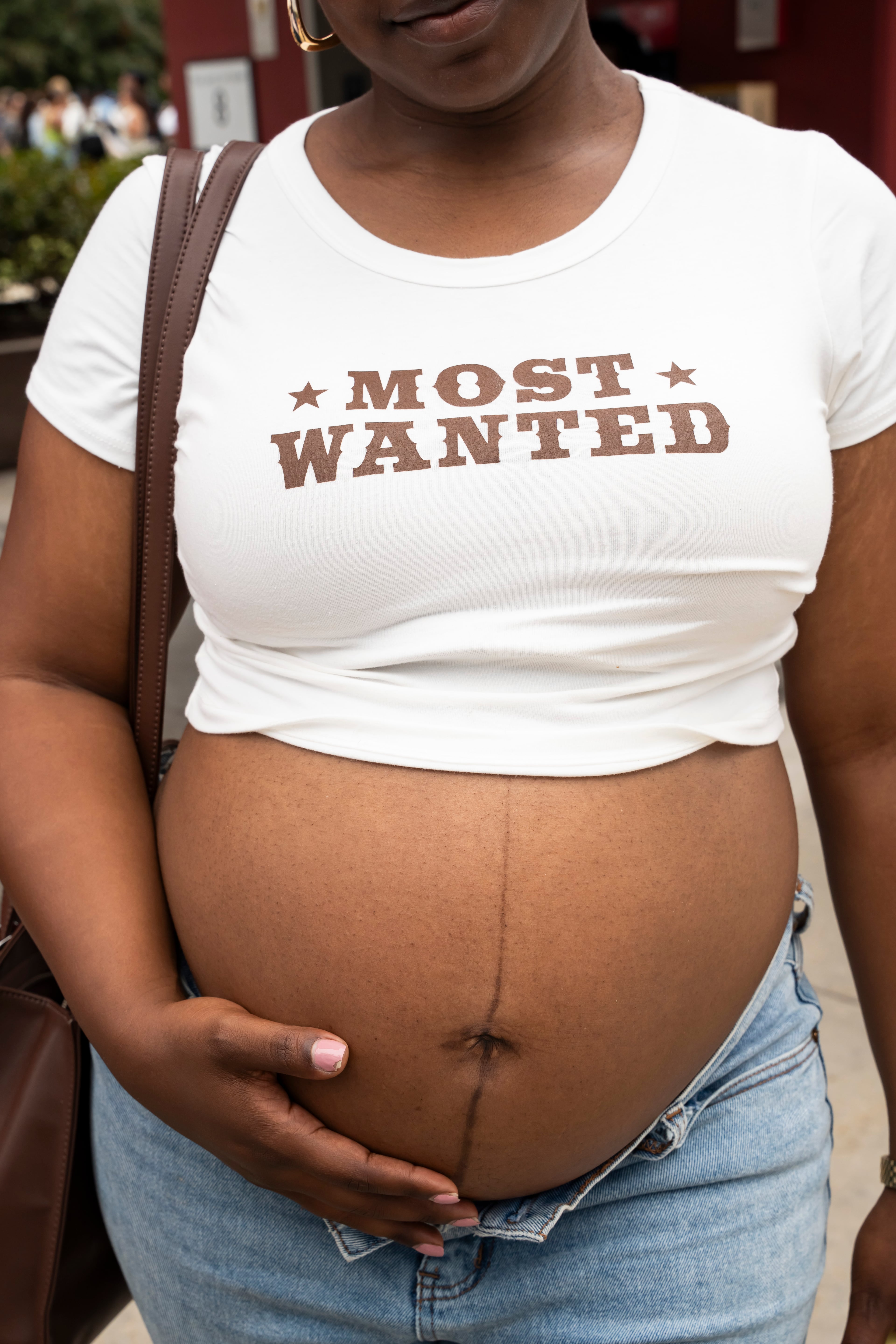 Shayla Weatherred holds her baby bump while wearing a "most wanted" T-shirt in line outside Beyoncé's Cowboy Carter concert in Atlanta on Thursday, July 10, 2025. (Olivia Bowdoin for the AJC)
