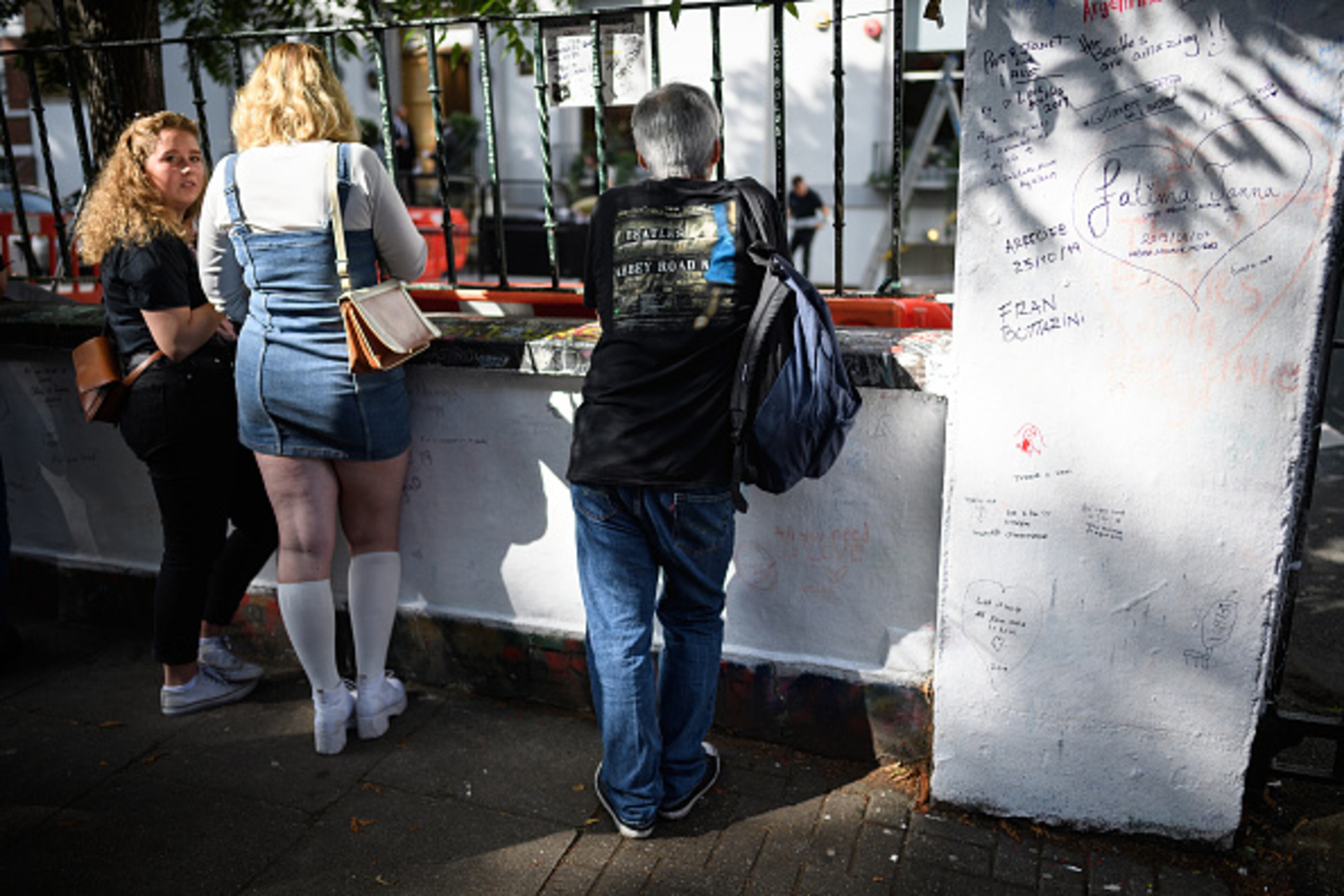LONDON, ENGLAND - AUGUST 08: People look through the railings of Abbey Road studios, fifty years since the iconic album cover for "Abbey Road" by the Beatles was taken, on August 08, 2019 in London, England. The zebra crossing is just outside the recording studios and has become a popular location for music fans visiting London. (Photo by Leon Neal/Getty Images)