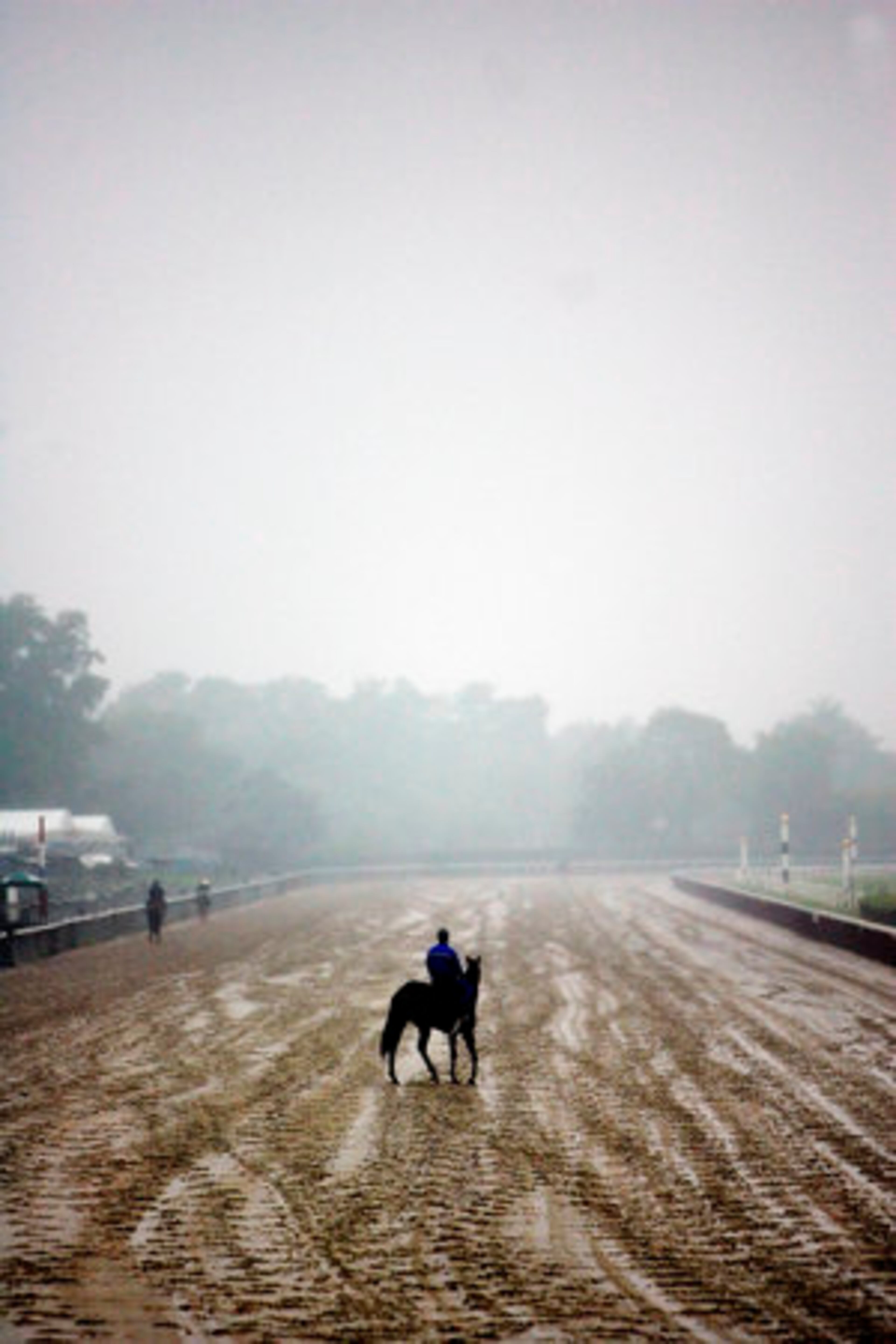 A horse and rider pause in the middle of a muddy track during a workout at Belmont Park in Elmont, N.Y., on Wednesday.