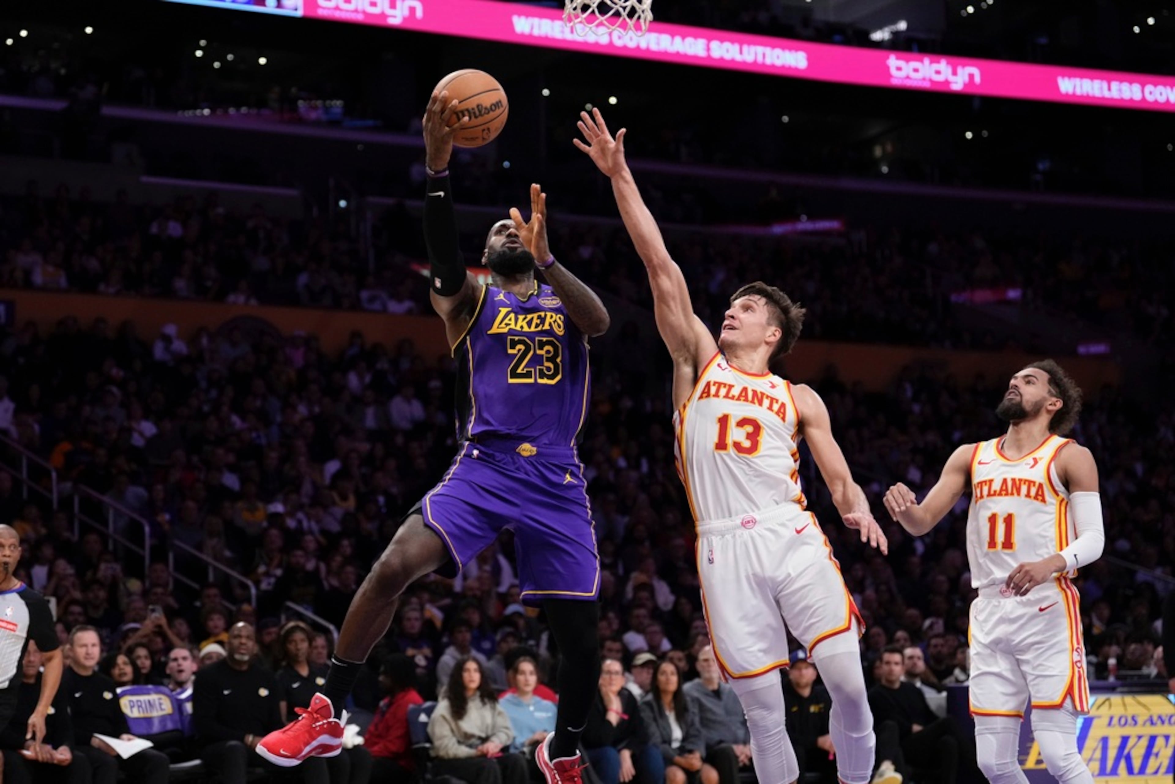 Los Angeles Lakers forward LeBron James, left, shoots as Atlanta Hawks' Bogdan Bogdanović, center, and Trae Young defend during the first half of an NBA basketball game, Friday, Jan. 3, 2025, in Los Angeles. (AP Photo/Mark J. Terrill)