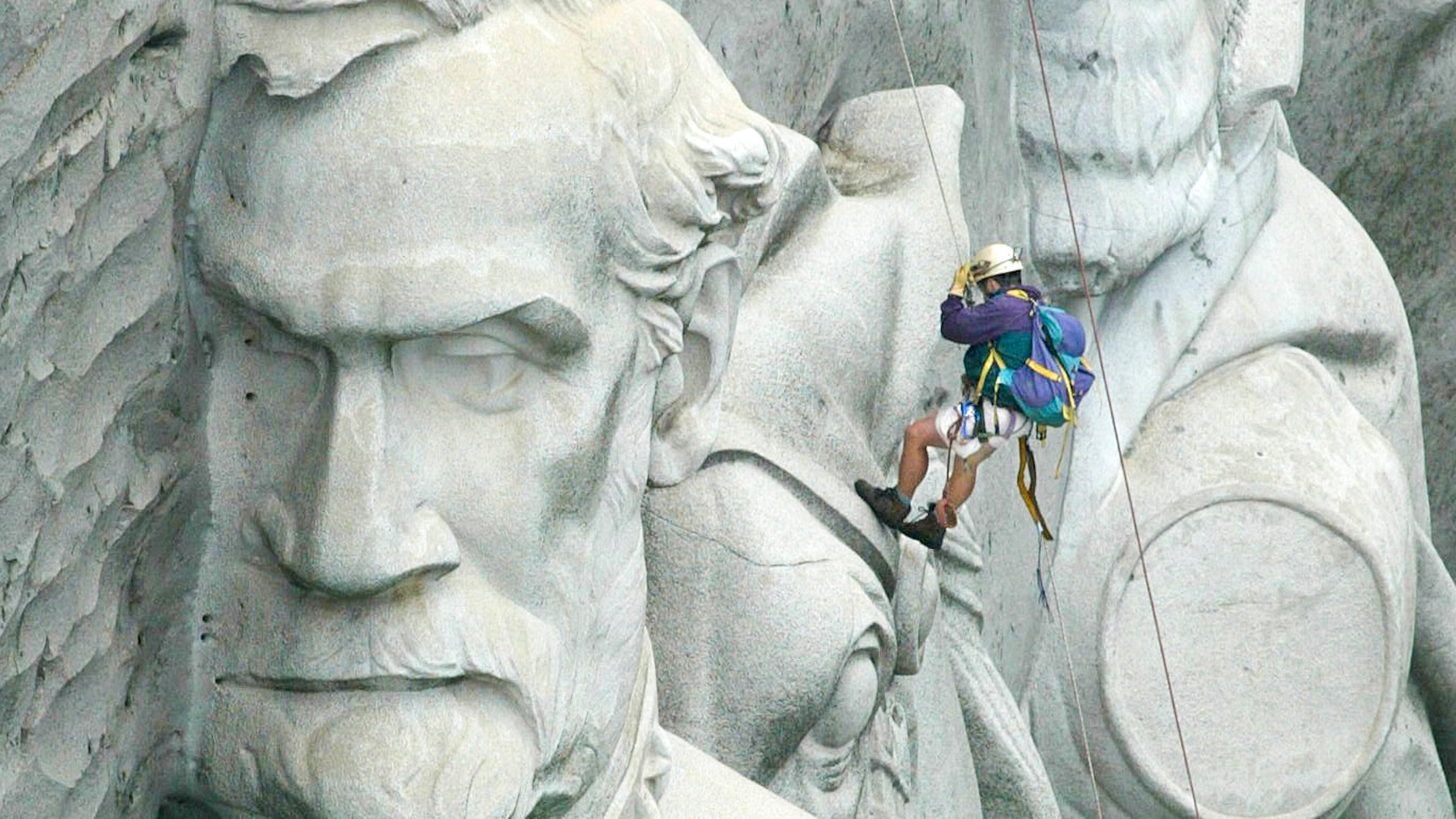 A sandblaster cleaning the carving of three Confederate leaders on Stone Mountain. John Spink, jspink@ajc.com