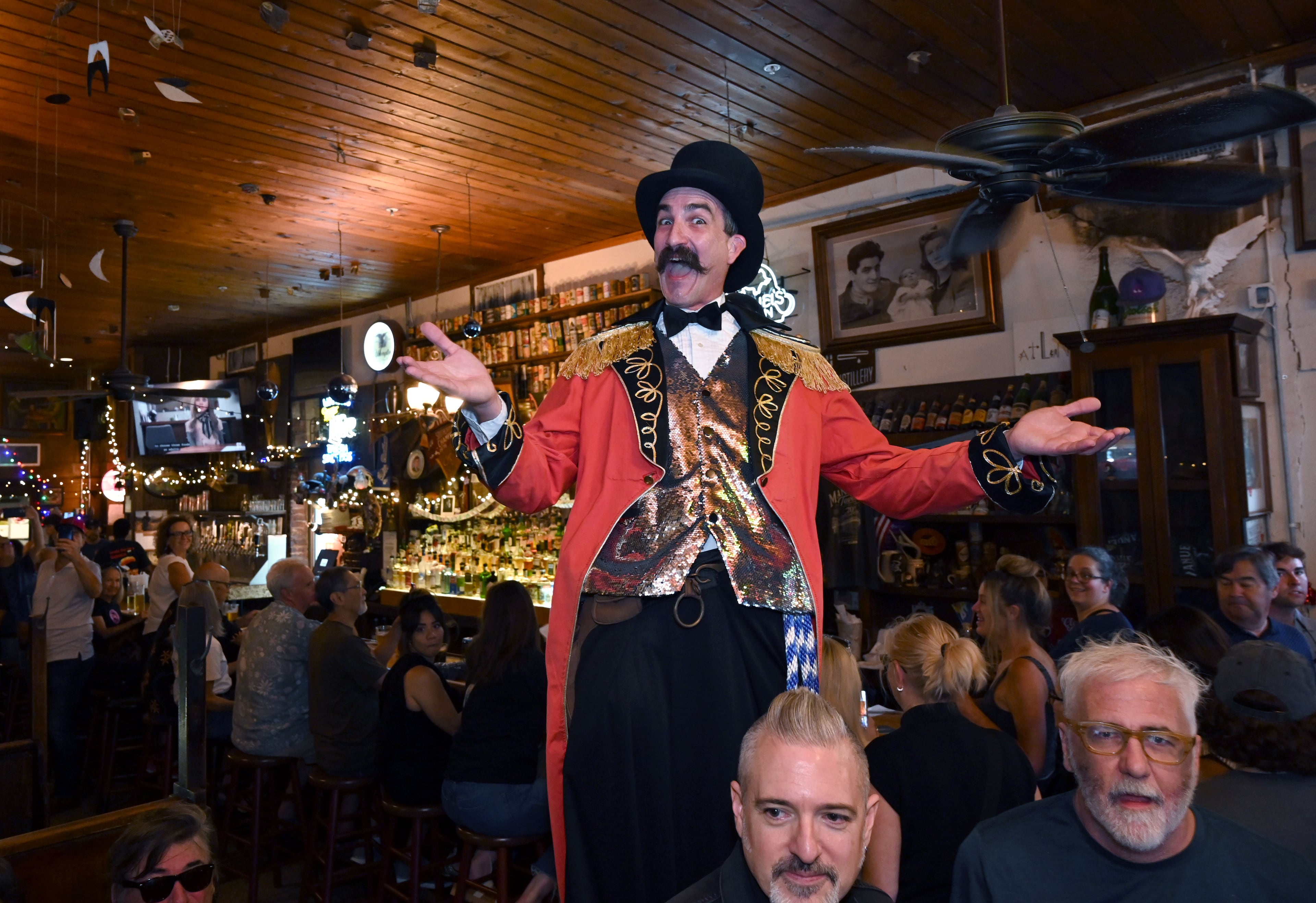 A one-man circus performer on stilts entertains guests during Manuel’s Tavern’s 70th anniversary celebration. (Hyosub Shin/AJC)