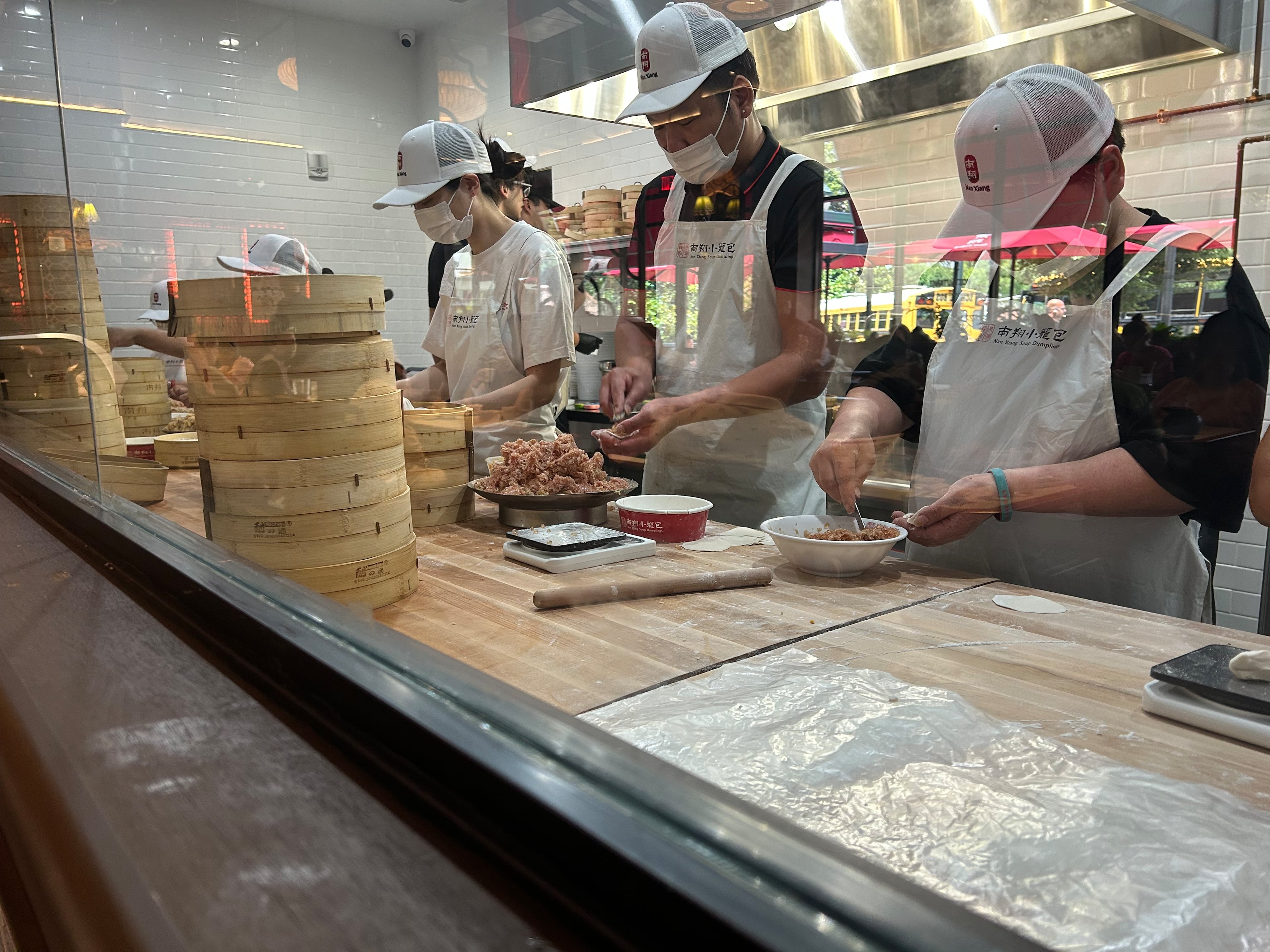 A production line of workers weigh out balls of dough, roll them and fold up to 18 pleats per soup dumpling. (Candy Hom for the AJC)