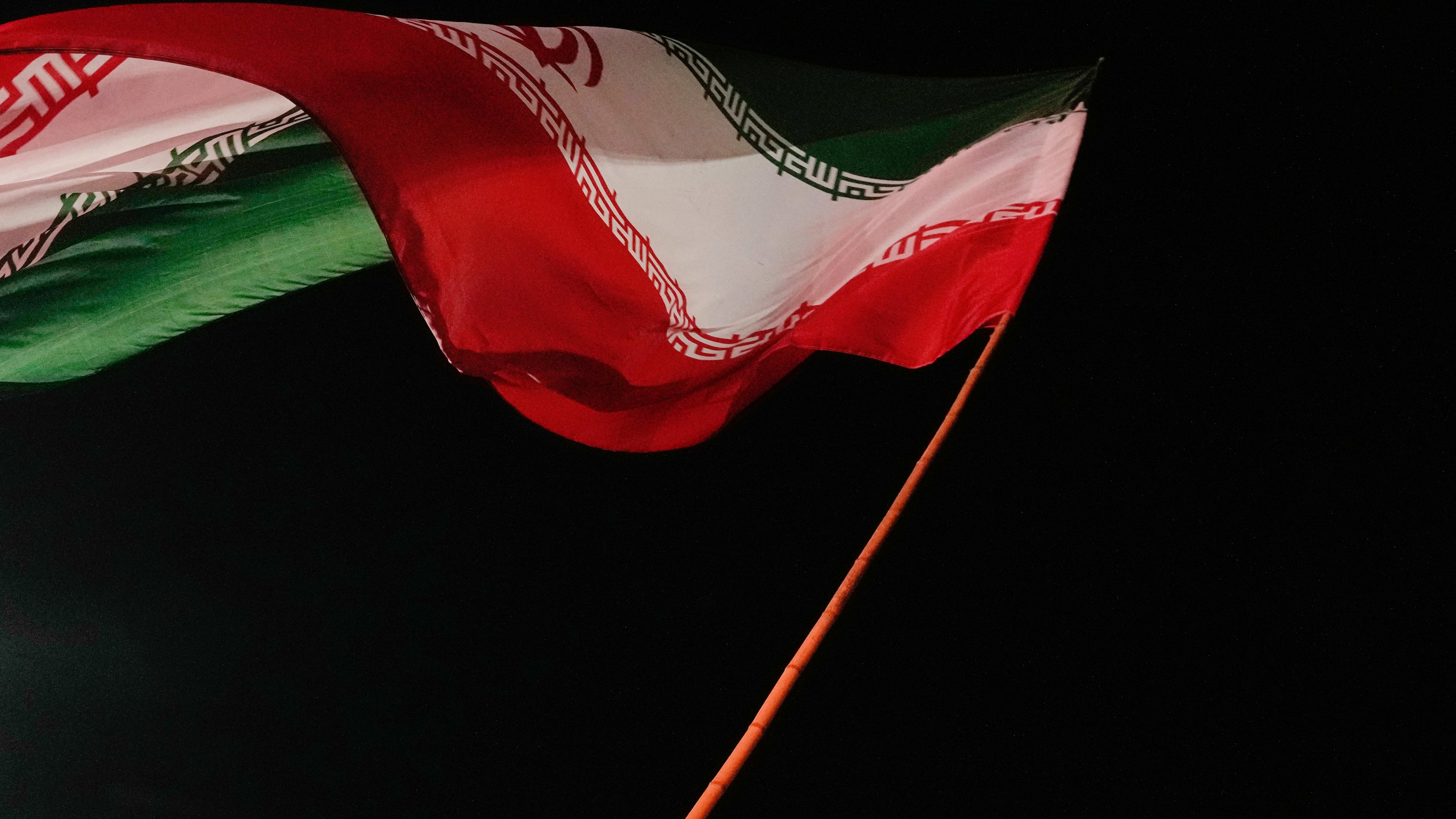 A man waves an Iranian flag during a pro-government gathering at a square in Tehran, Iran, Tuesday, Aug. 11, 2026. (AP Photo/Vahid Salemi)