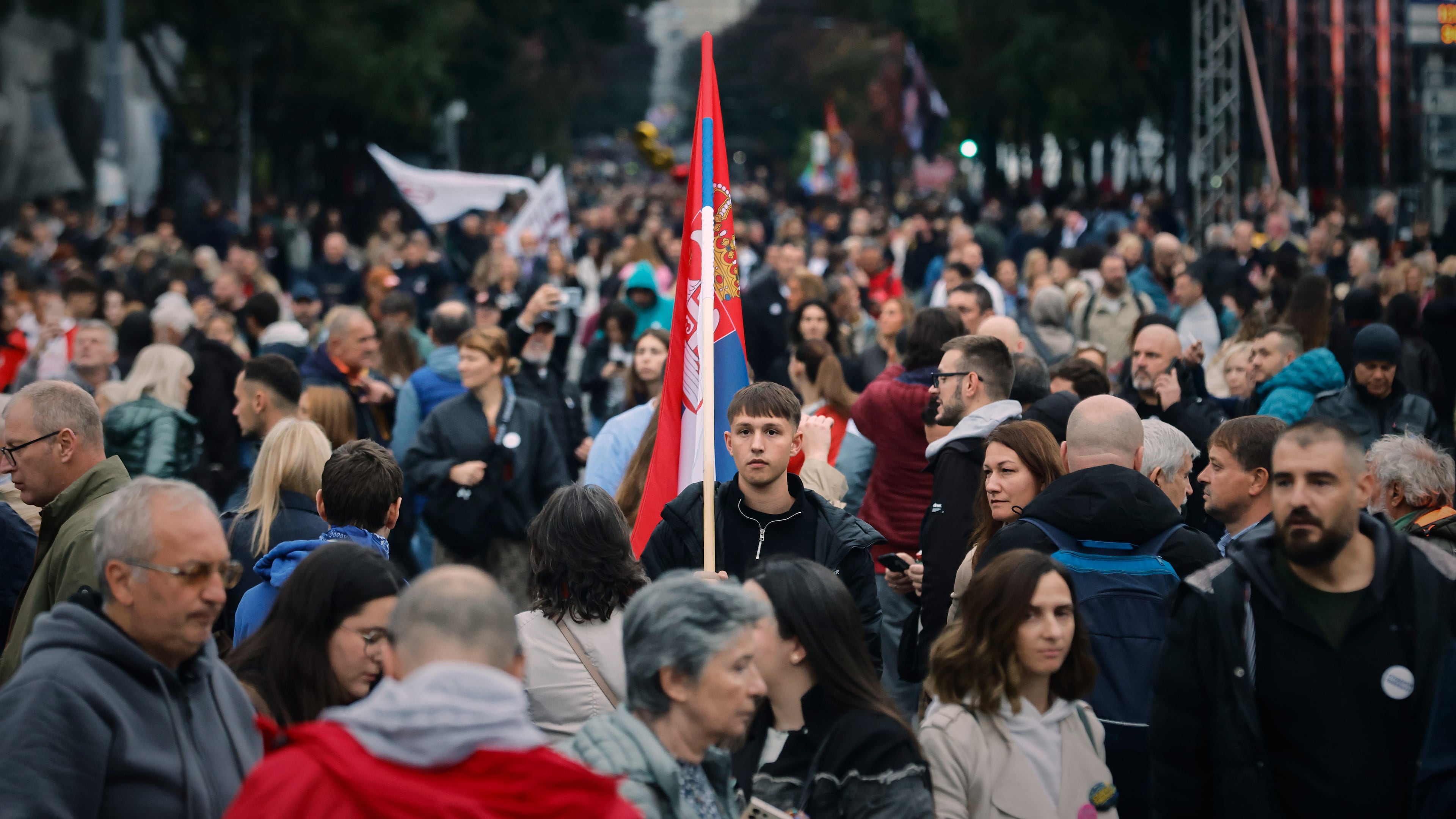 A young man holds a Serbian flag as people gather for the final "Student List – Students Win" rally ahead of a parliamentary election in Belgrade, Serbia, Thursday, Oct. 22, 2026. (AP Photo/Marko Drobnjakovic)