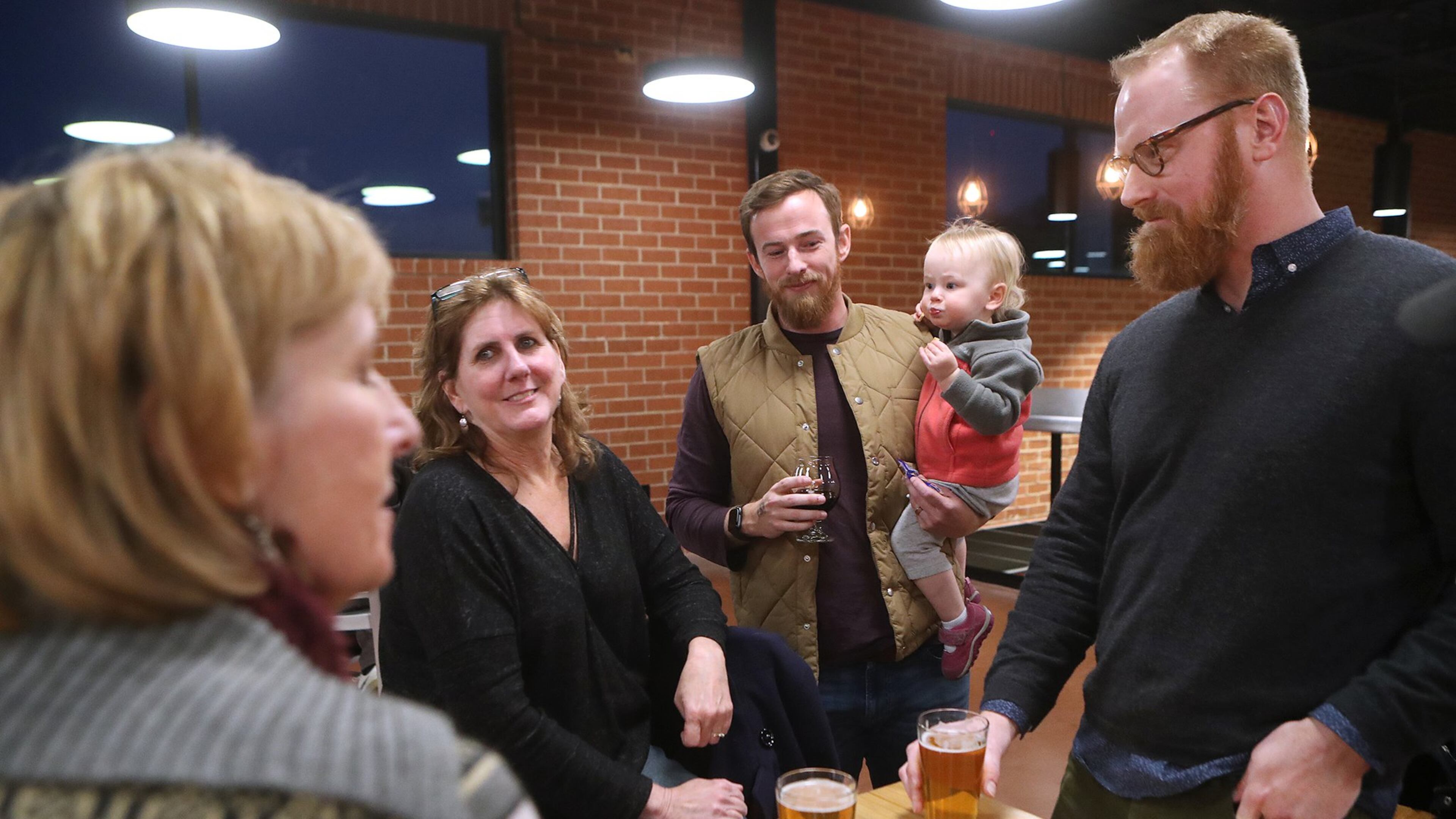 Furloughed workers Daria Labinsky (from left), Maureen Hill, Chip Daymude with his daughter Penny, 18-months, and Nathan Jordan discuss the shutdown at Sweetwater Brewing Company during an event offering free food and beer to furloughed federal workers on Thursday, Jan. 10, 2019, in Atlanta.
