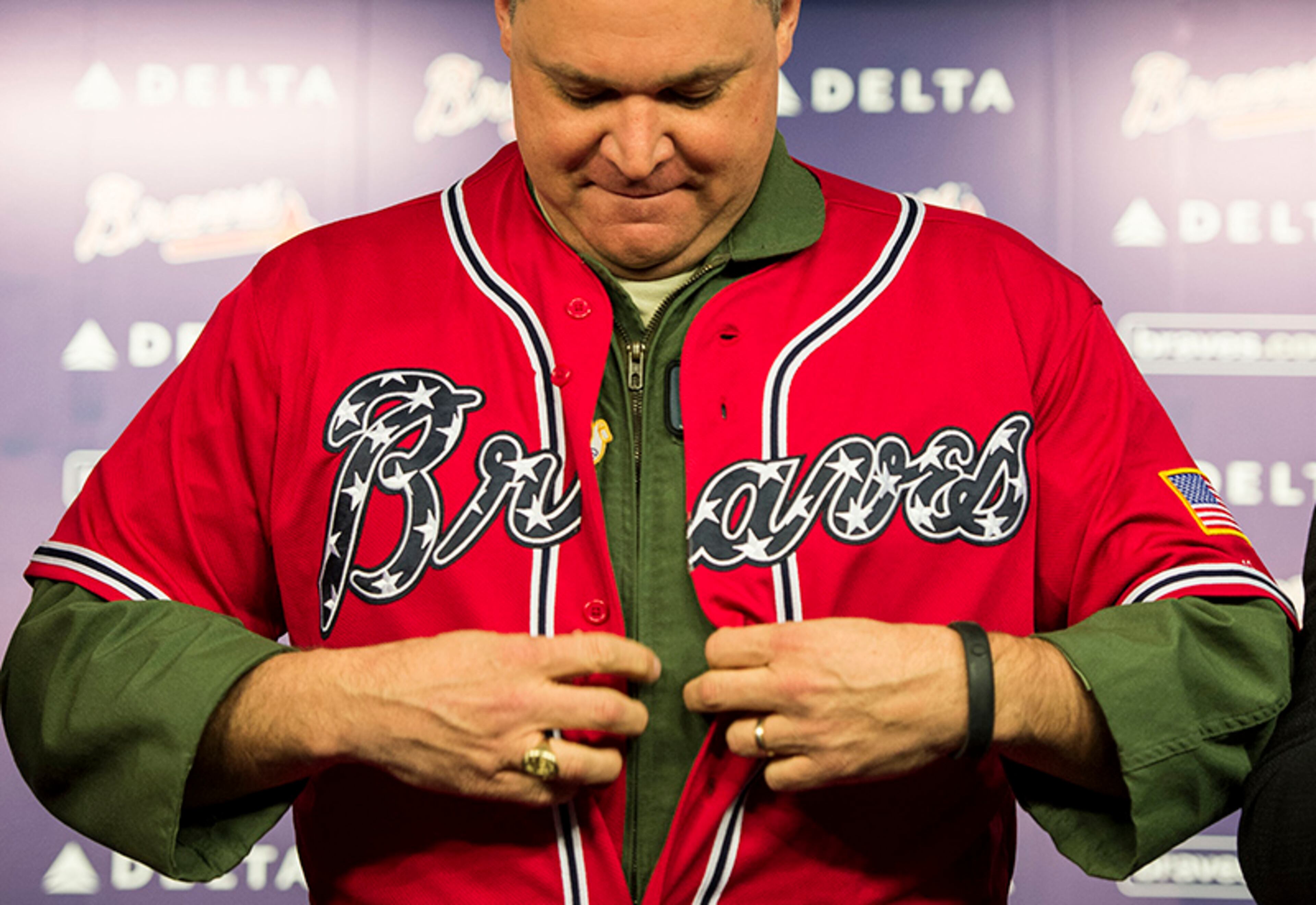 Maj. Gen. Jim Butterworth buttons up the Braves' new military appreciation alternative jersey at Turner Field Wednesday in Atlanta.