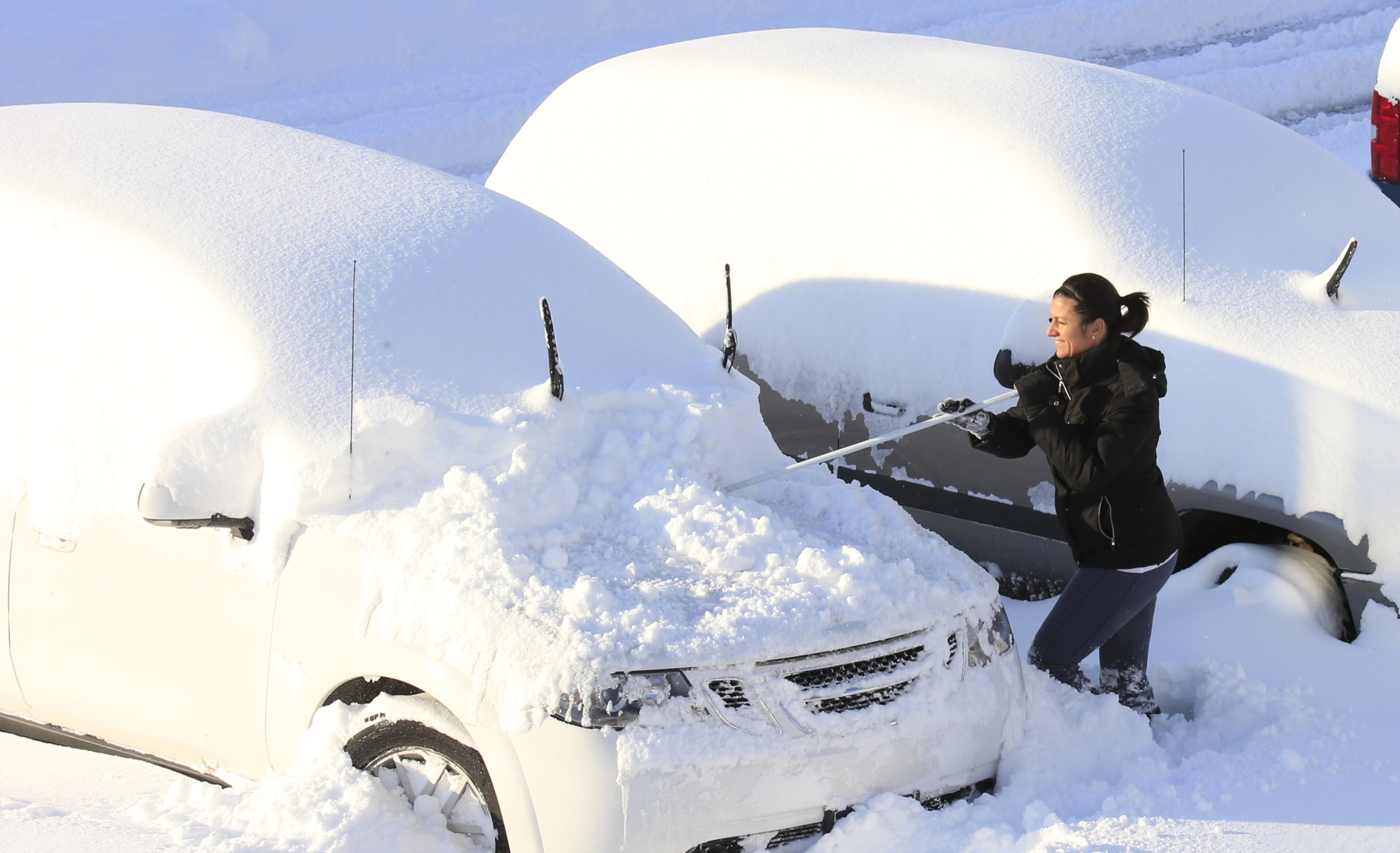 Christine Bloom works to clear snow off her vehicle to try and make it to work in Hamburg, N.Y., on Wednesday, Nov. 19, 2014. A ferocious storm dumped massive piles of snow on parts of upstate New York, trapping residents in their homes and stranding motorists on roadways, as temperatures in all 50 states fell to freezing or below. (AP Photo/The Buffalo News, Harry Scull Jr.)