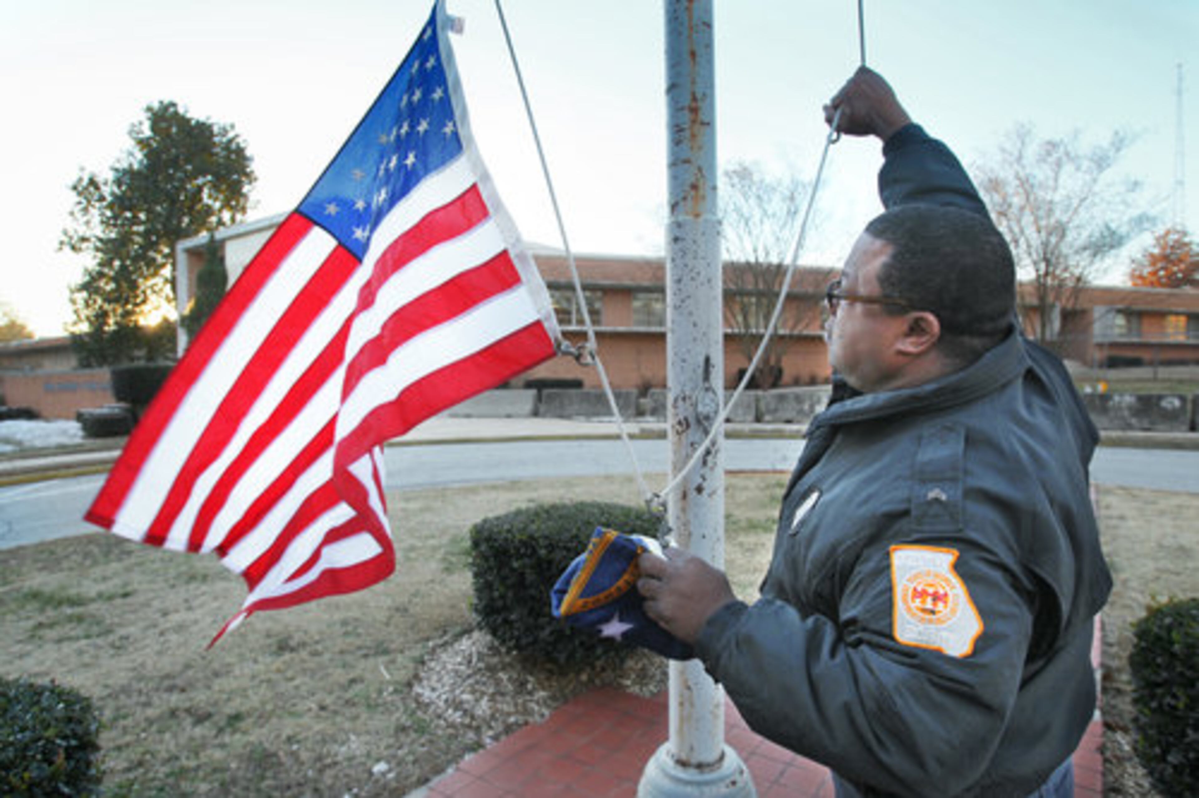 After the death of Chadwick LeCroy, the flag is raised at half-staff on Tuesday morning by Sgt. Anthony Hughes at the Department of Public Safety Headquarters in Atlanta.