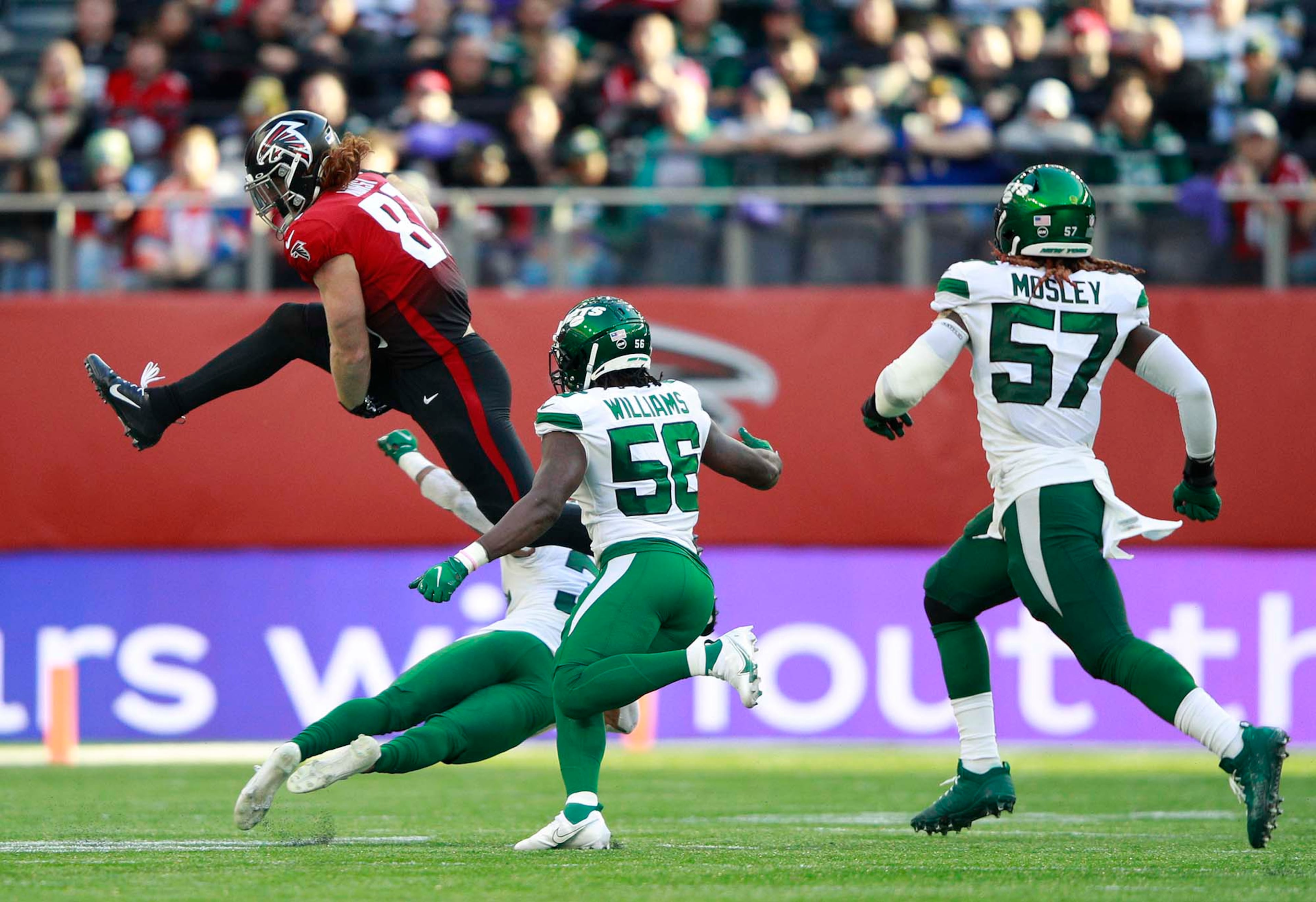 Falcons tight end Hayden Hurst (81) leaps over a tackle by New York Jets defenders during the second half Sunday, Oct. 10, 2021, at the Tottenham Hotspur stadium in London, England. (Ian Walton/AP)