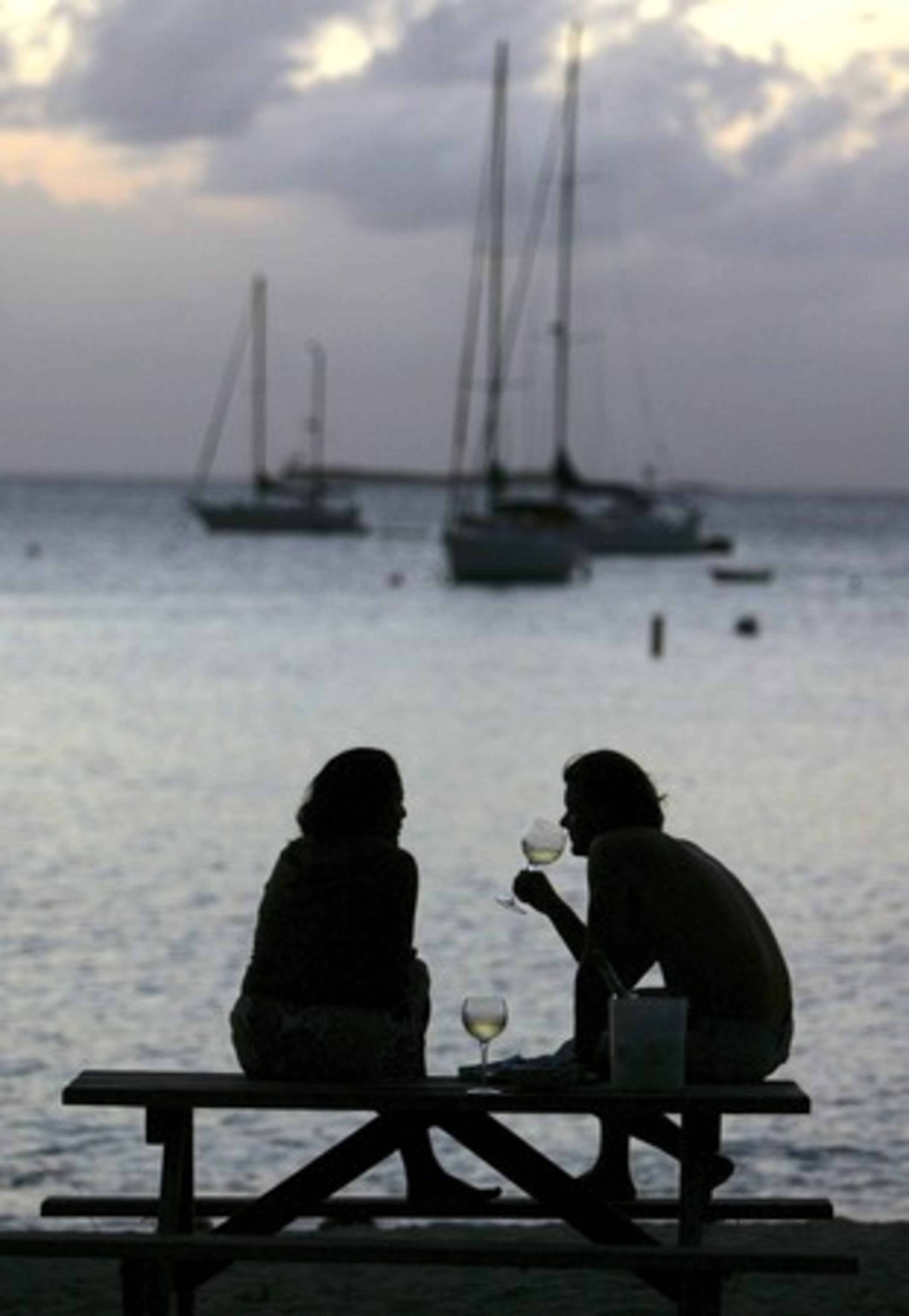 A couple drinks white wine at the end of the day on a beach near Charlotte Amalie, St. Thomas, U.S. Virgin Islands.