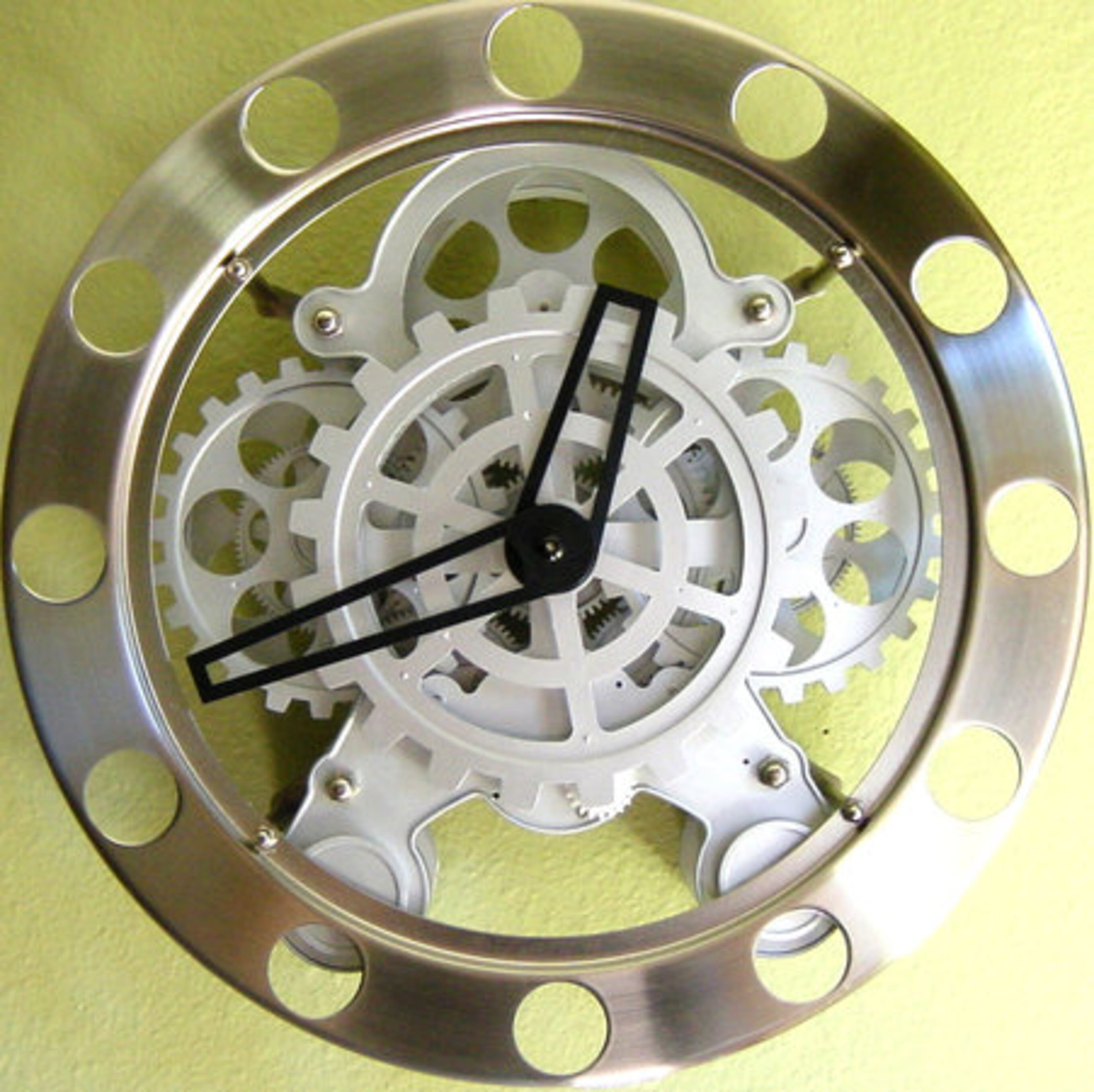 The Gear Clock was designed by Wil Van Den Bos. Stainless steel rim houses the exposed innards of the secret workings of this ultra-cool clock. 14" in diameter. Stainless steel outer frame, plastic gears and metal hands.
