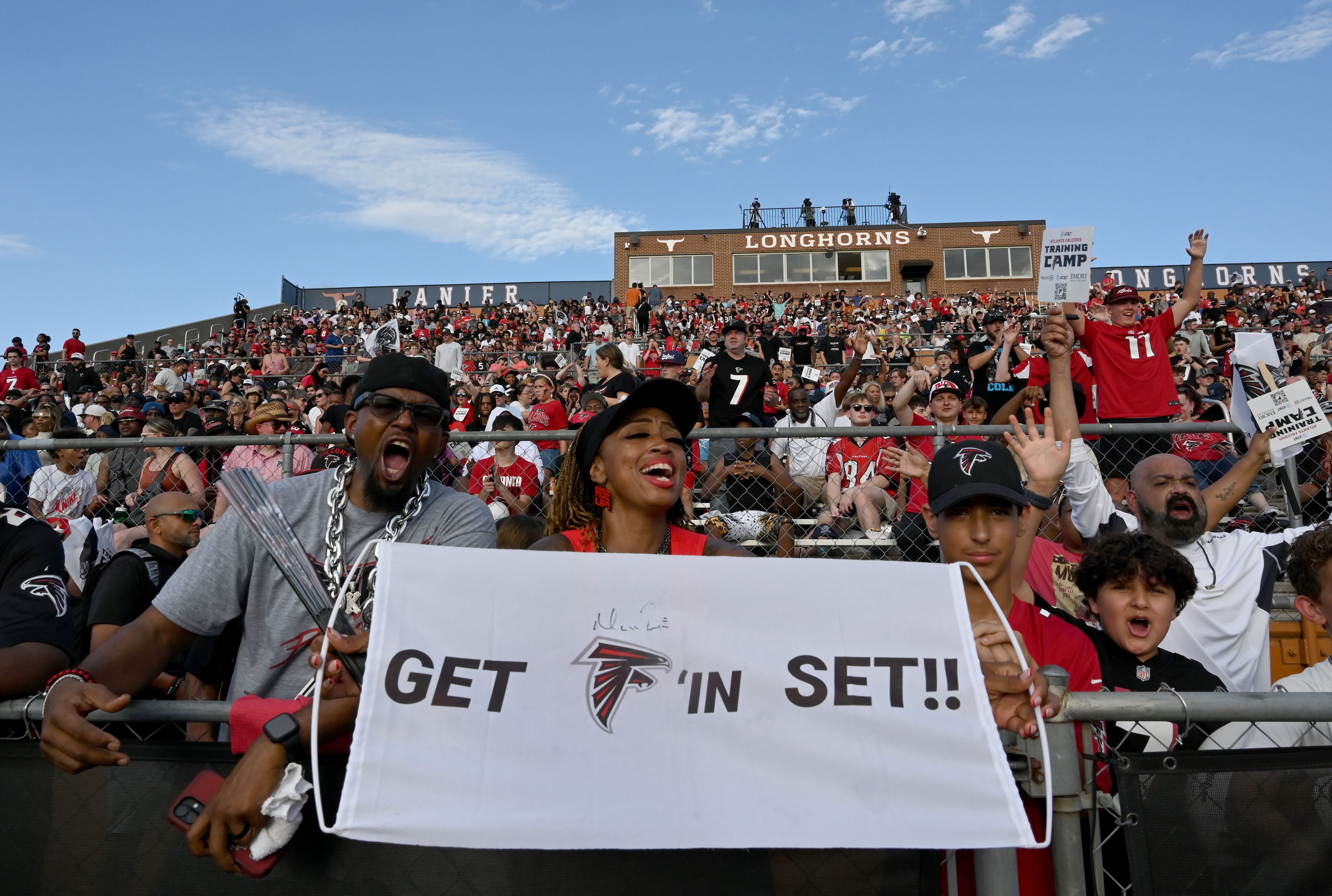 Football fans cheer as they watch their favorite players in action during the Atlanta Falcons' "Saturday Night Lights" practice Saturday, Aug. 8, 2026, at Lanier High School in Sugar Hill. (Hyosub Shin/AJC)