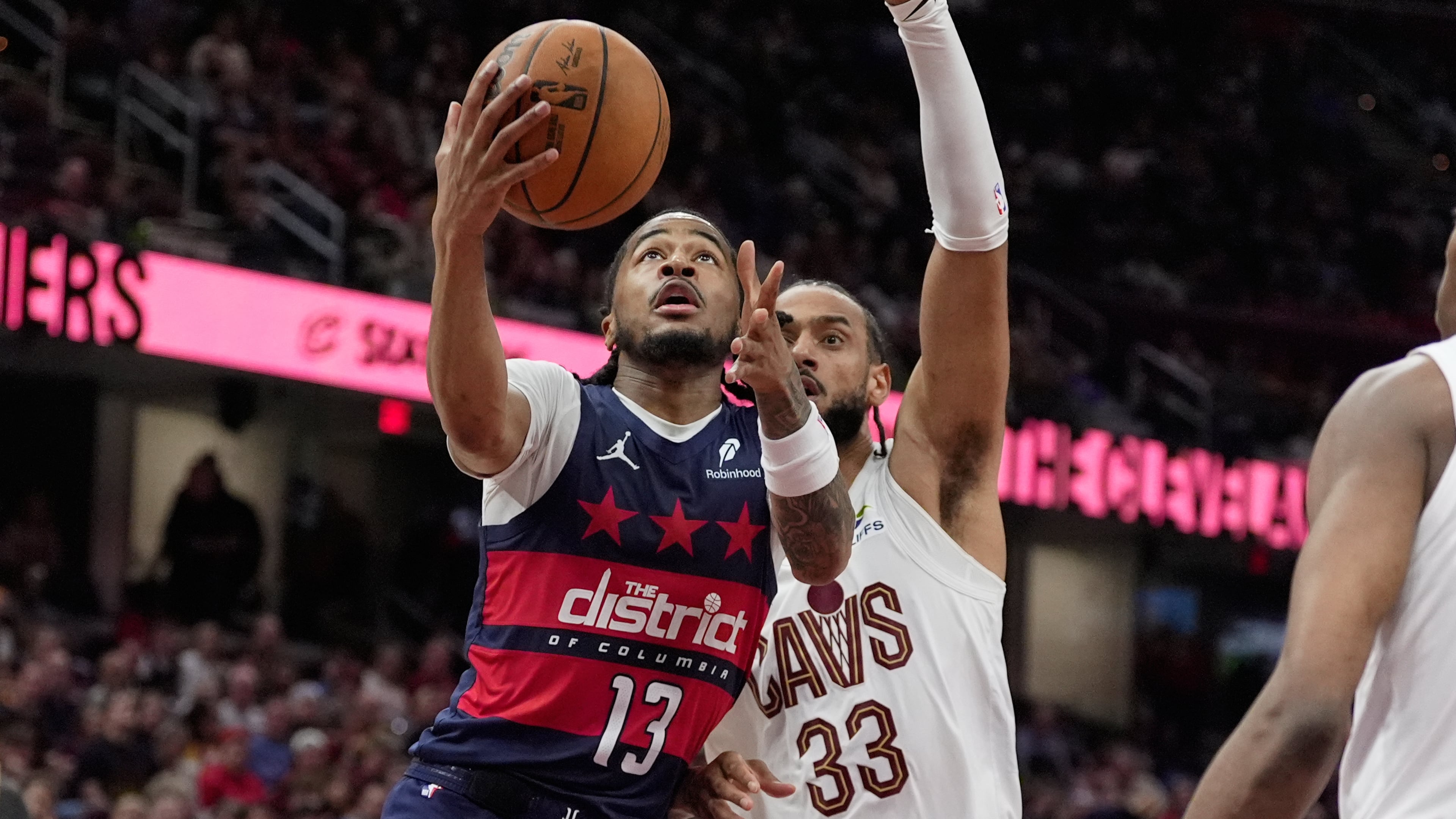 Washington Wizards guard Sharife Cooper (13) goes to the basket past Cleveland Cavaliers forward Olivier Sarr (33) in the second half of an NBA basketball game in Cleveland, Sunday, April 12, 2026. (AP Photo/Sue Ogrocki)