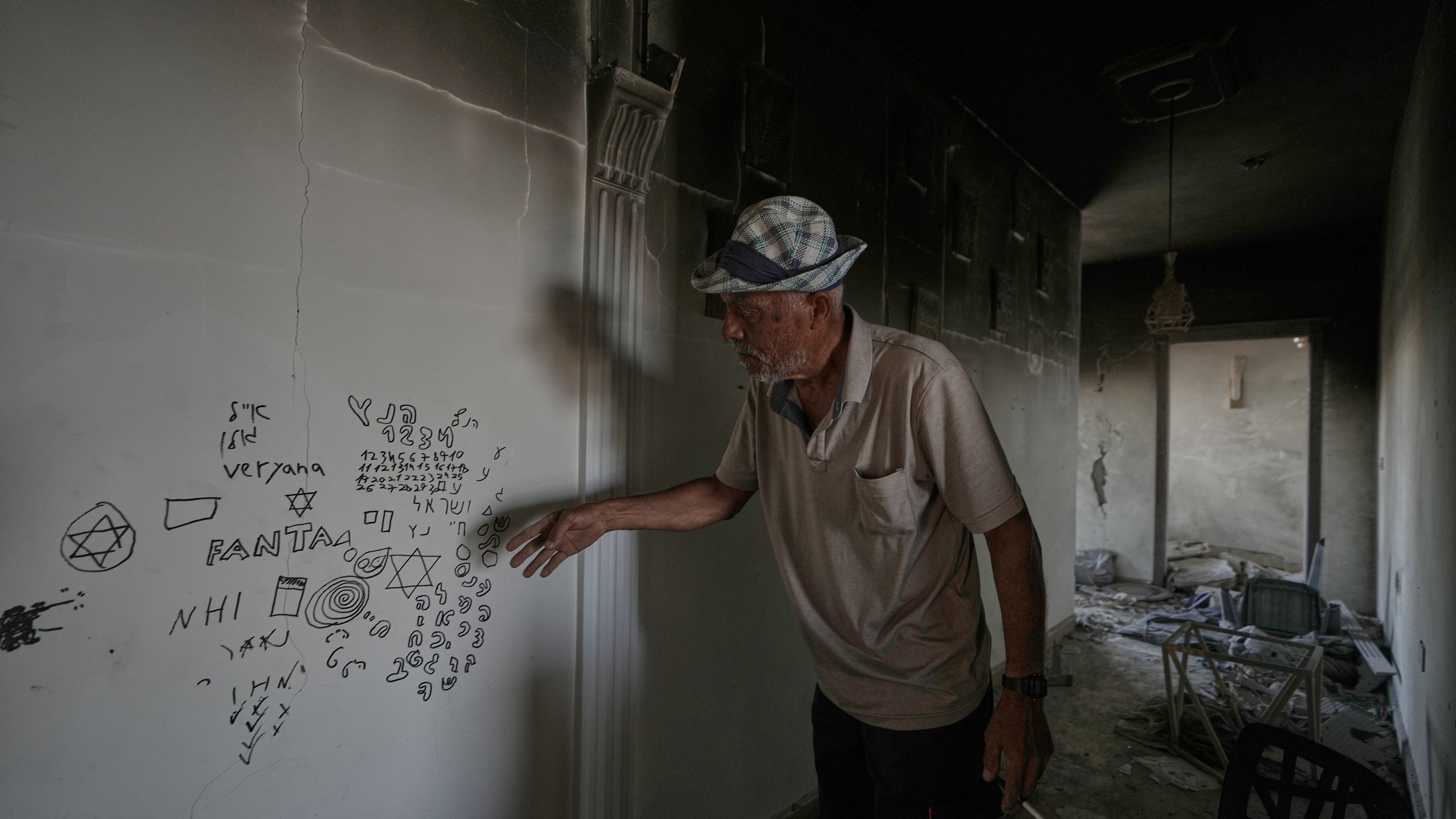 A Lebanese man points to Hebrew writing left by Israeli soldiers inside his destroyed home in the village of Zawtar al-Gharbieh, southern Lebanon, Wednesday, Aug. 5, 2026.(AP Photo/Mohammed Zaatari)