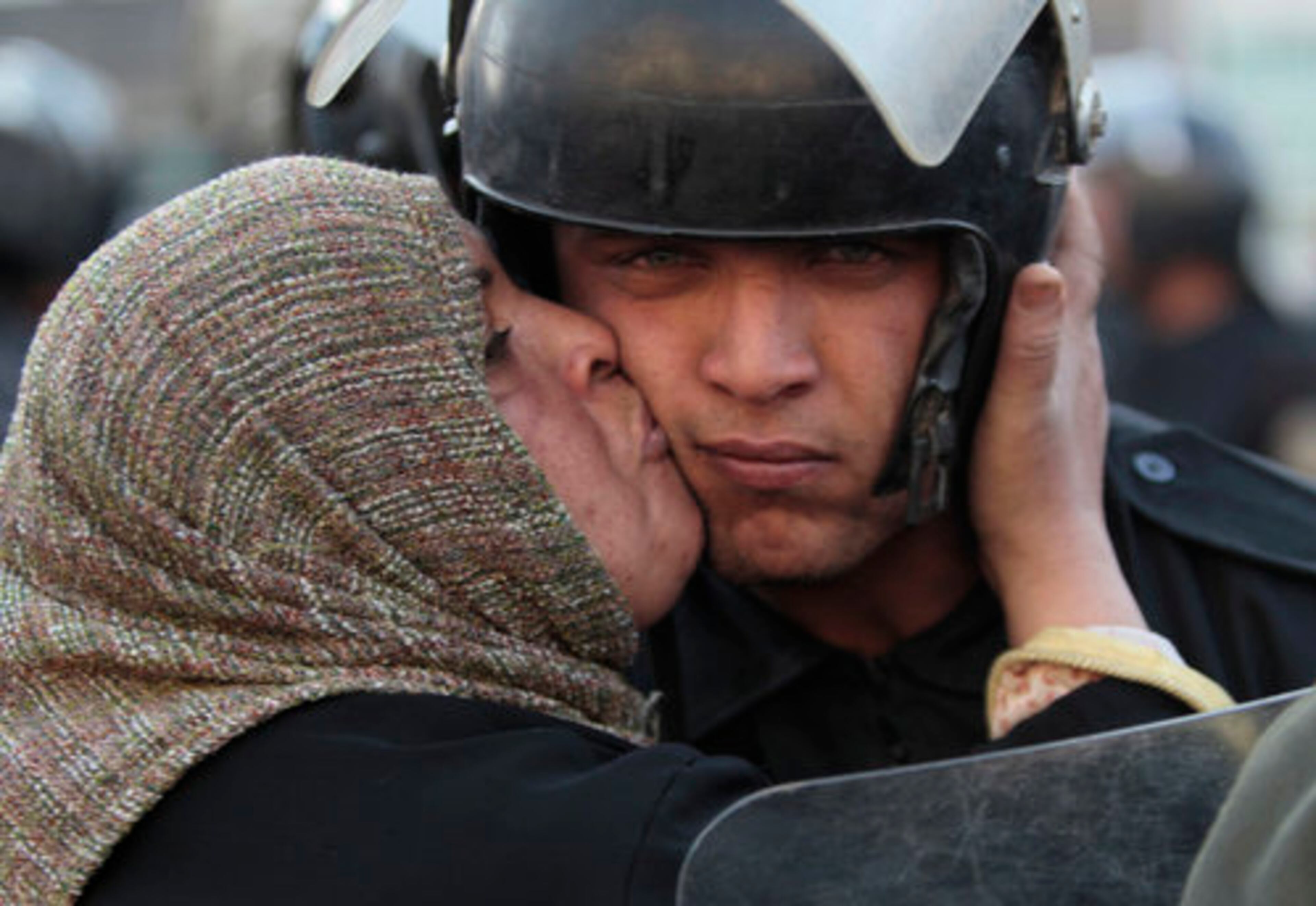 FILE -In this Jan. 28, 2011 file photo, an Egyptian anti-government activist kisses a riot police officer following clashes in Cairo, Egypt.