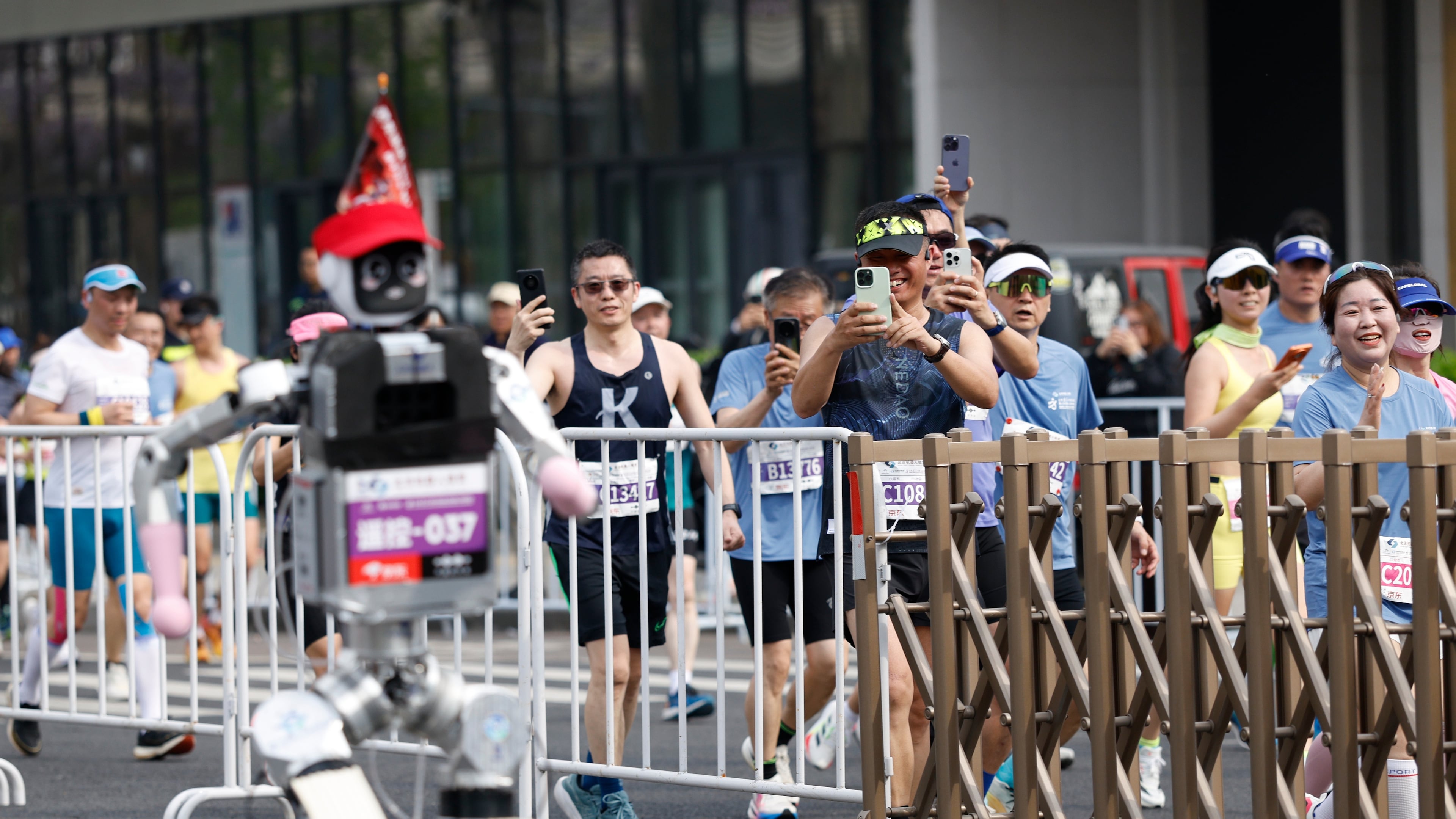 Runners take pictures of a humanoid robot in the second Beijing E-Town Half Marathon and Humanoid Robot Half Marathon in Beijing Sunday, April 19, 2026. (Haruna Furuhashi/Pool Photo via AP)
