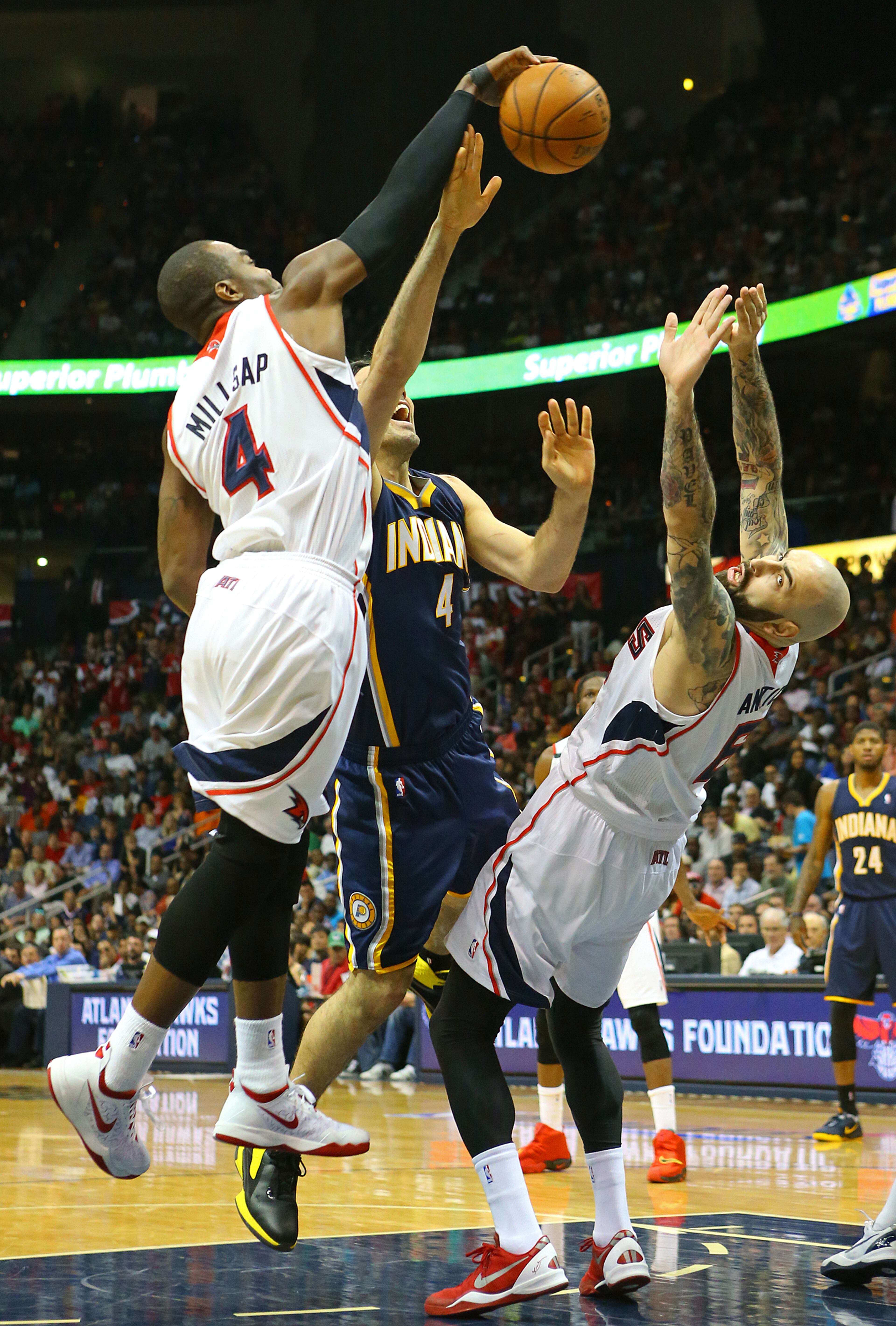 Hawks Paul Millsap gets some air to block a shot by Pacers Luis Scola with help from Pero Antic on defense during the first half of their NBA playoff game on Thursday, April 24, 2014, in Atlanta. CURTIS COMPTON / CCOMPTON@AJC.COM