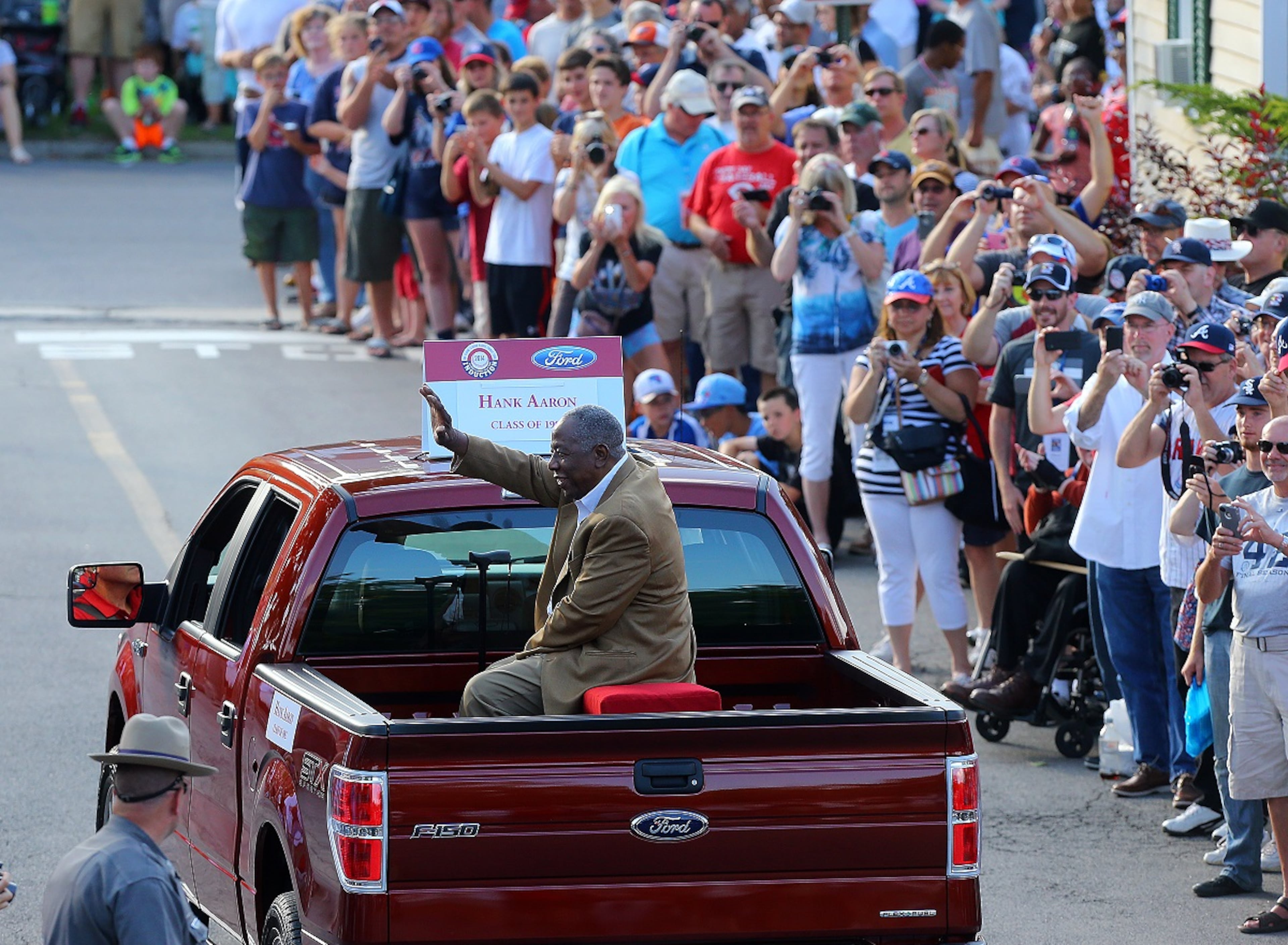 Hank Aaron waves to fans from the back of a pickup truck during the Hall of Fame Legends Parade down Main Street on Saturday, July 26, 2014, in Cooperstown. CURTIS COMPTON / CCOMPTON@AJC.COM
